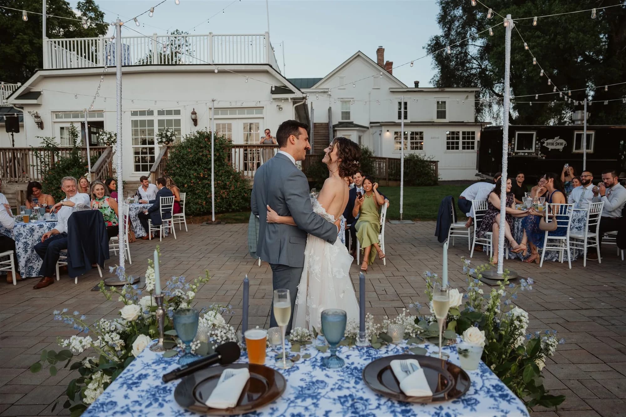 Bride and groom share a kiss at the sweetheart table on Rixey Manor's stone terrace at dusk