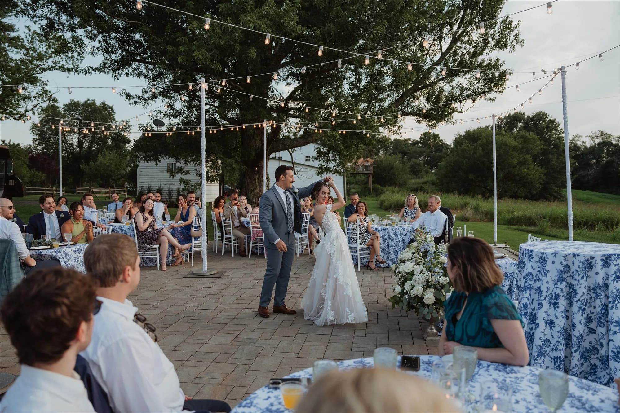 Bride and groom share first dance on stone patio under string lights at Rixey Manor outdoor reception