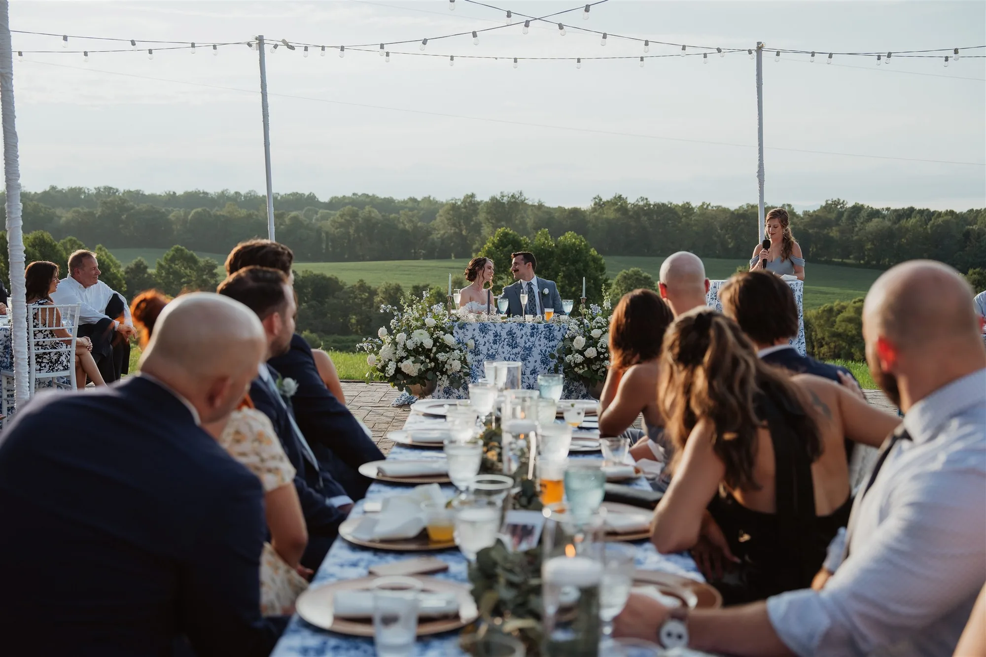Wedding couple at sweetheart table during outdoor reception at Rixey Manor with rolling Virginia countryside views