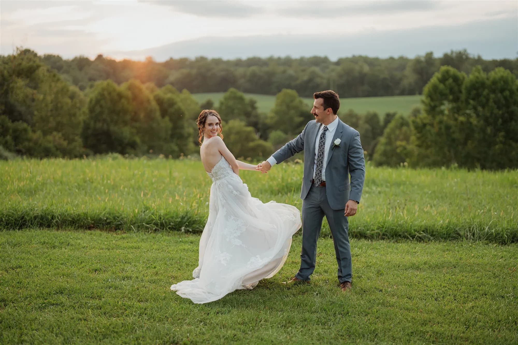 Bride and groom dancing in sunlit green fields at golden hour on the Rixey Manor grounds