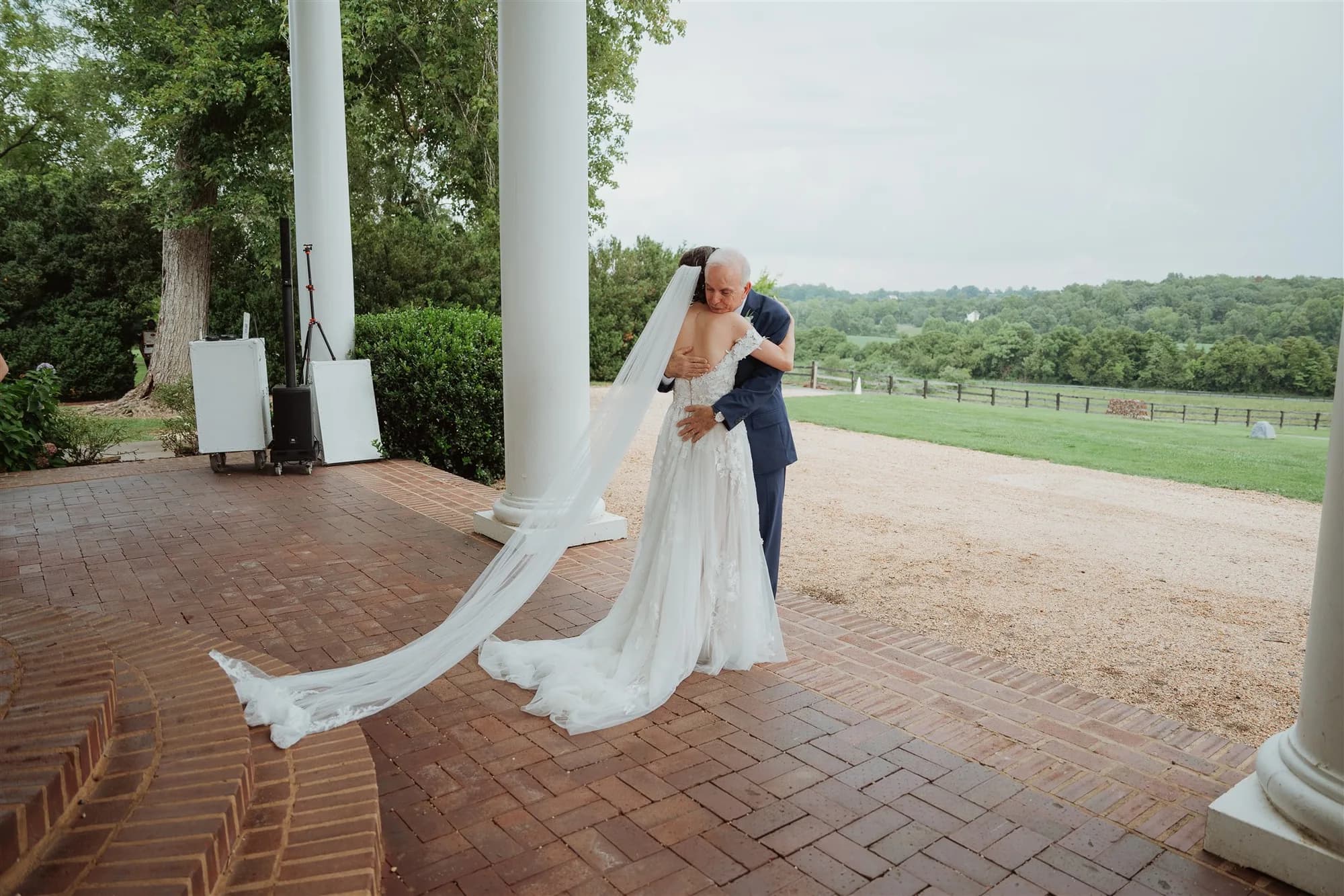 Groom dips bride in flowing veil on Rixey Manor's brick columned portico overlooking green Virginia countryside
