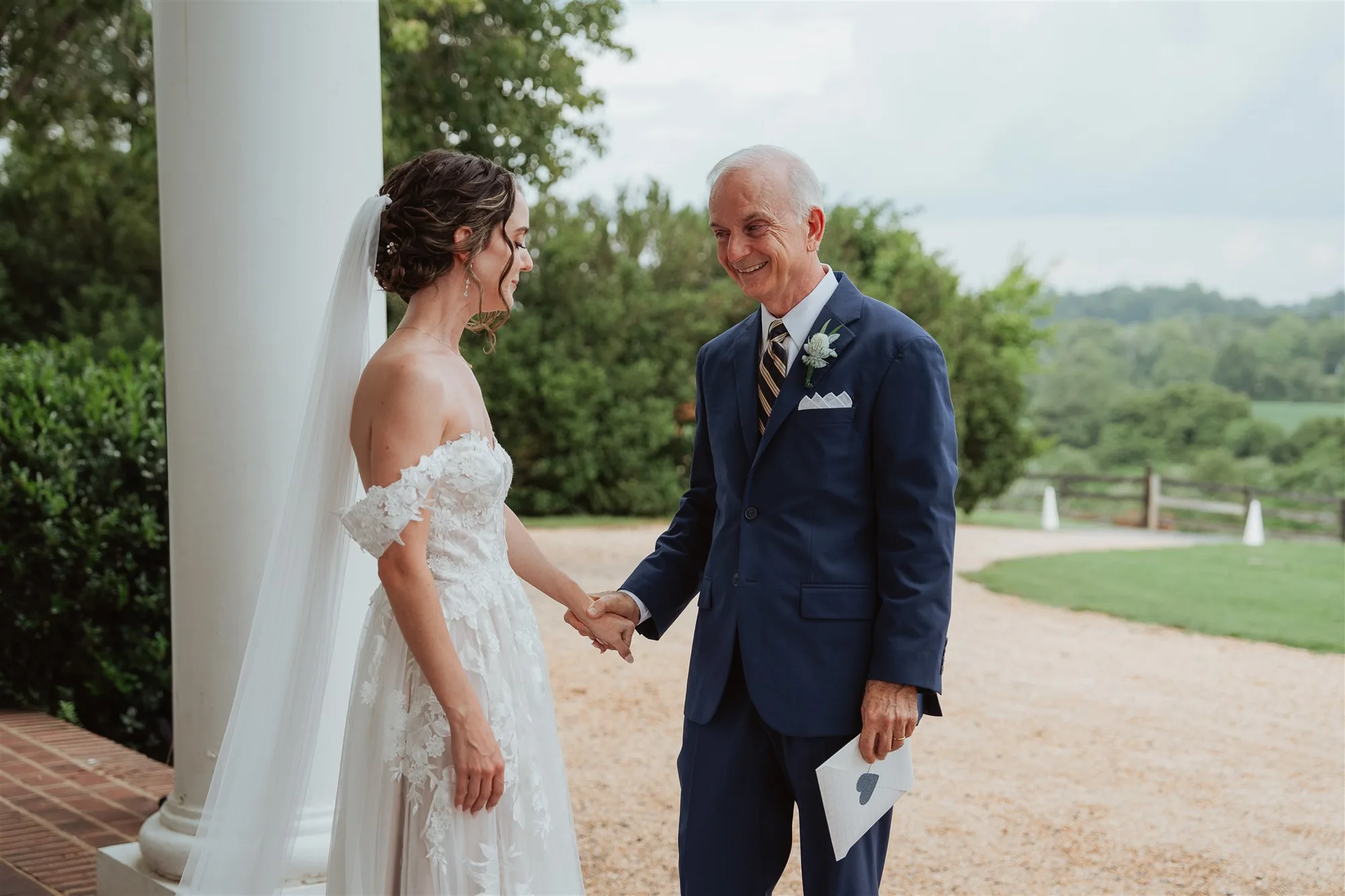 Bride and older gentleman share a warm first look handshake on the Rixey Manor columned portico