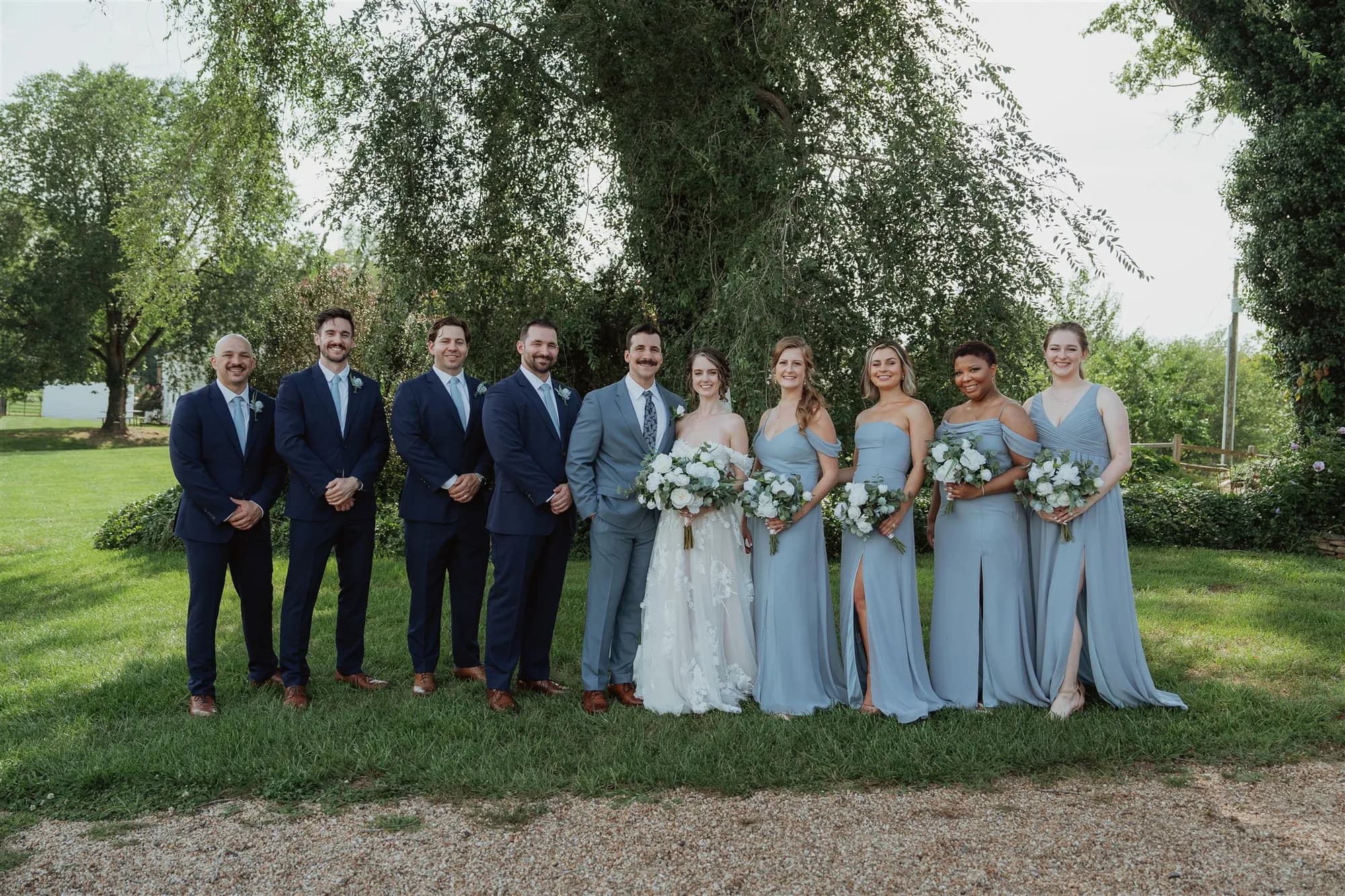 Wedding party portrait on Rixey Manor grounds with bride, groom, groomsmen in navy and bridesmaids in dusty blue