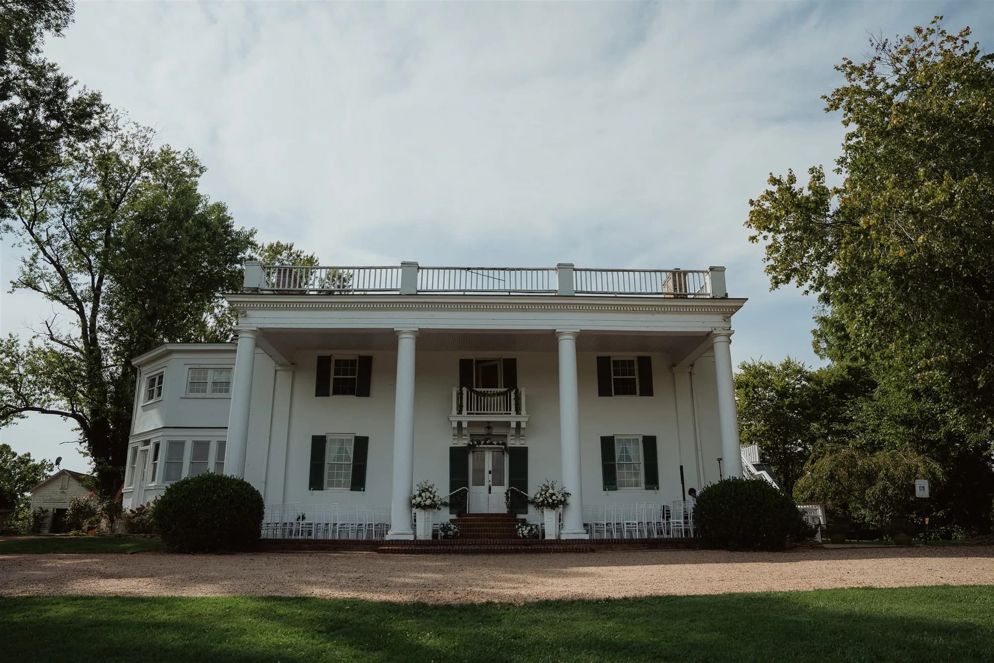 Front facade of Rixey Manor estate showing white columns, black shutters, and floral-decorated entrance steps