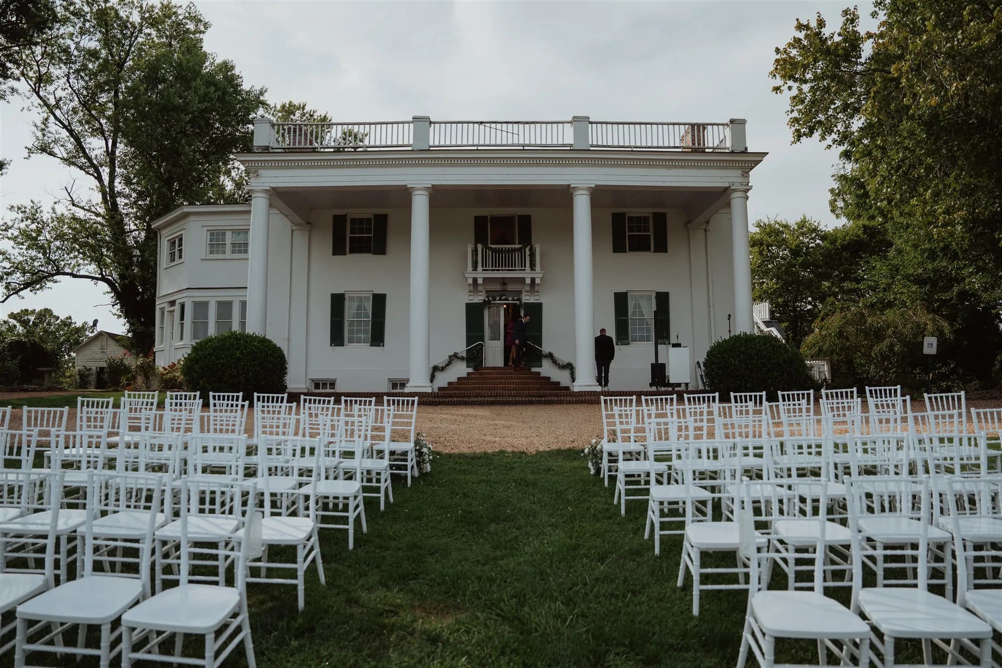 Rows of white chiavari chairs set for an outdoor ceremony on the lawn of Rixey Manor's columned estate