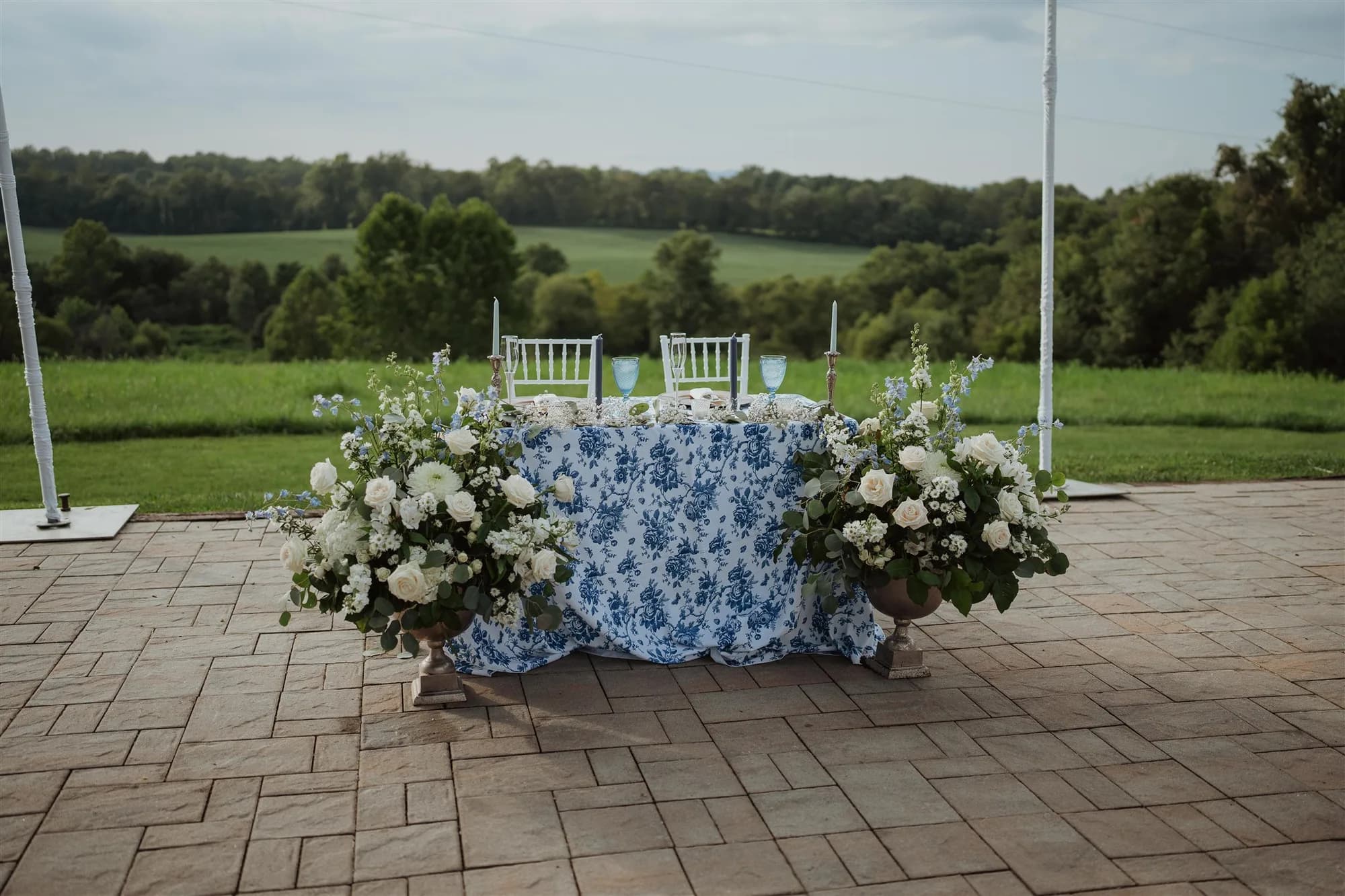Blue floral sweetheart table with white roses on stone terrace overlooking Rixey Manor's lush Virginia countryside