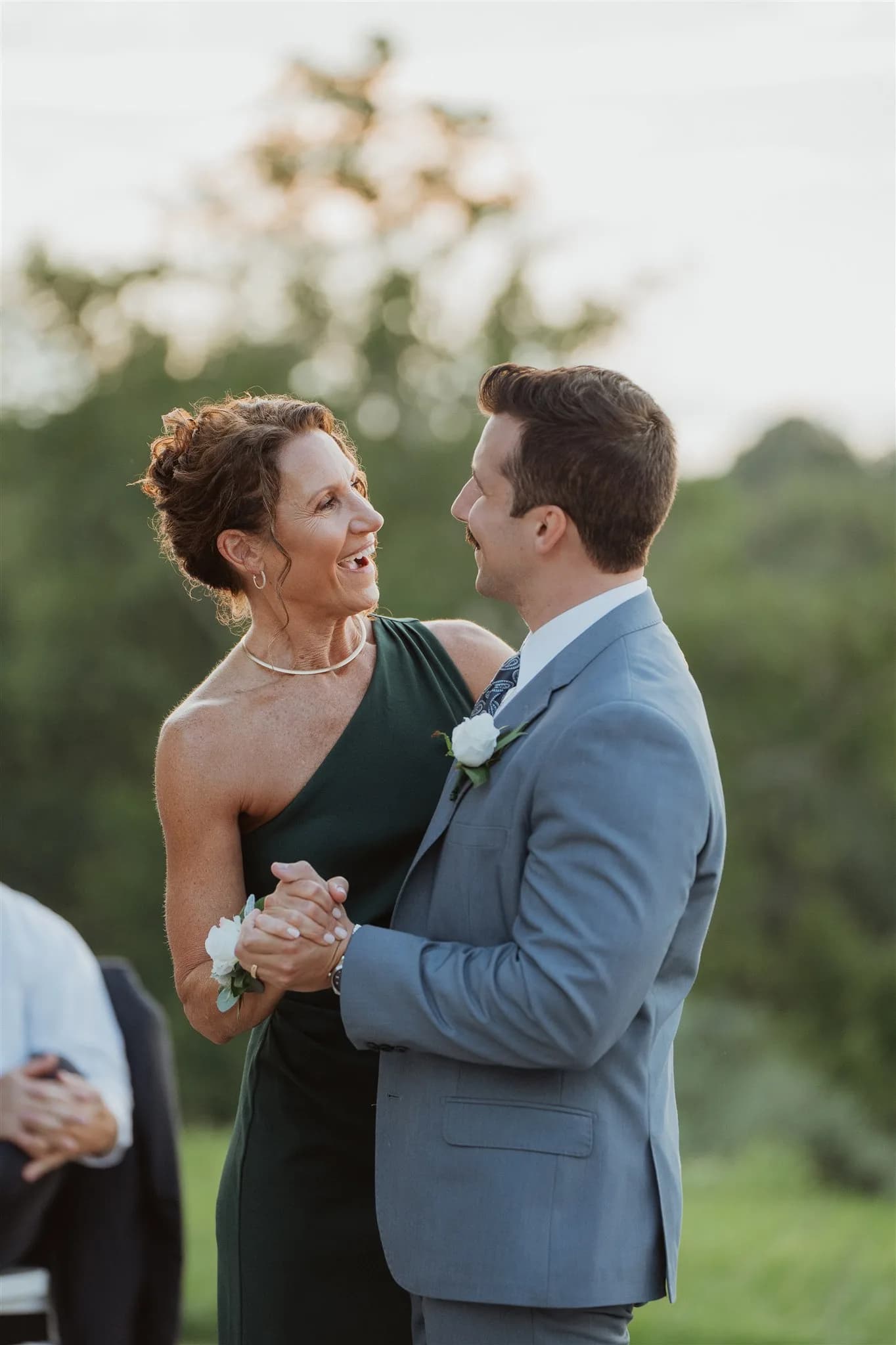 Groom and mother share a joyful laugh during mother-son dance at outdoor wedding reception