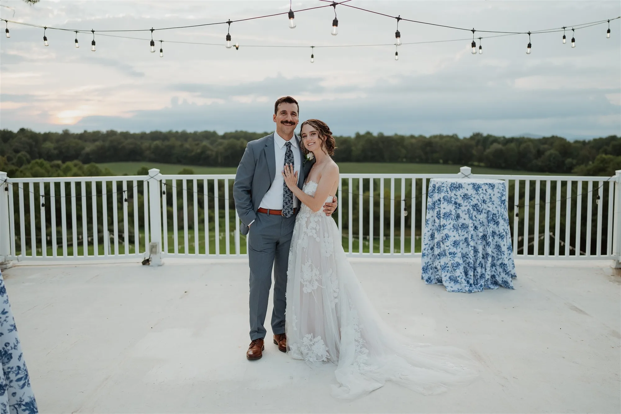 Bride and groom portrait on white terrace at Rixey Manor with rolling Virginia countryside at dusk