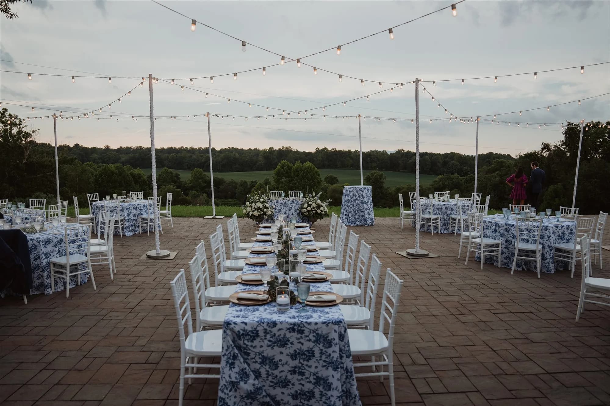 Outdoor reception terrace at Rixey Manor with blue floral linens, string lights, and sweeping Virginia countryside views