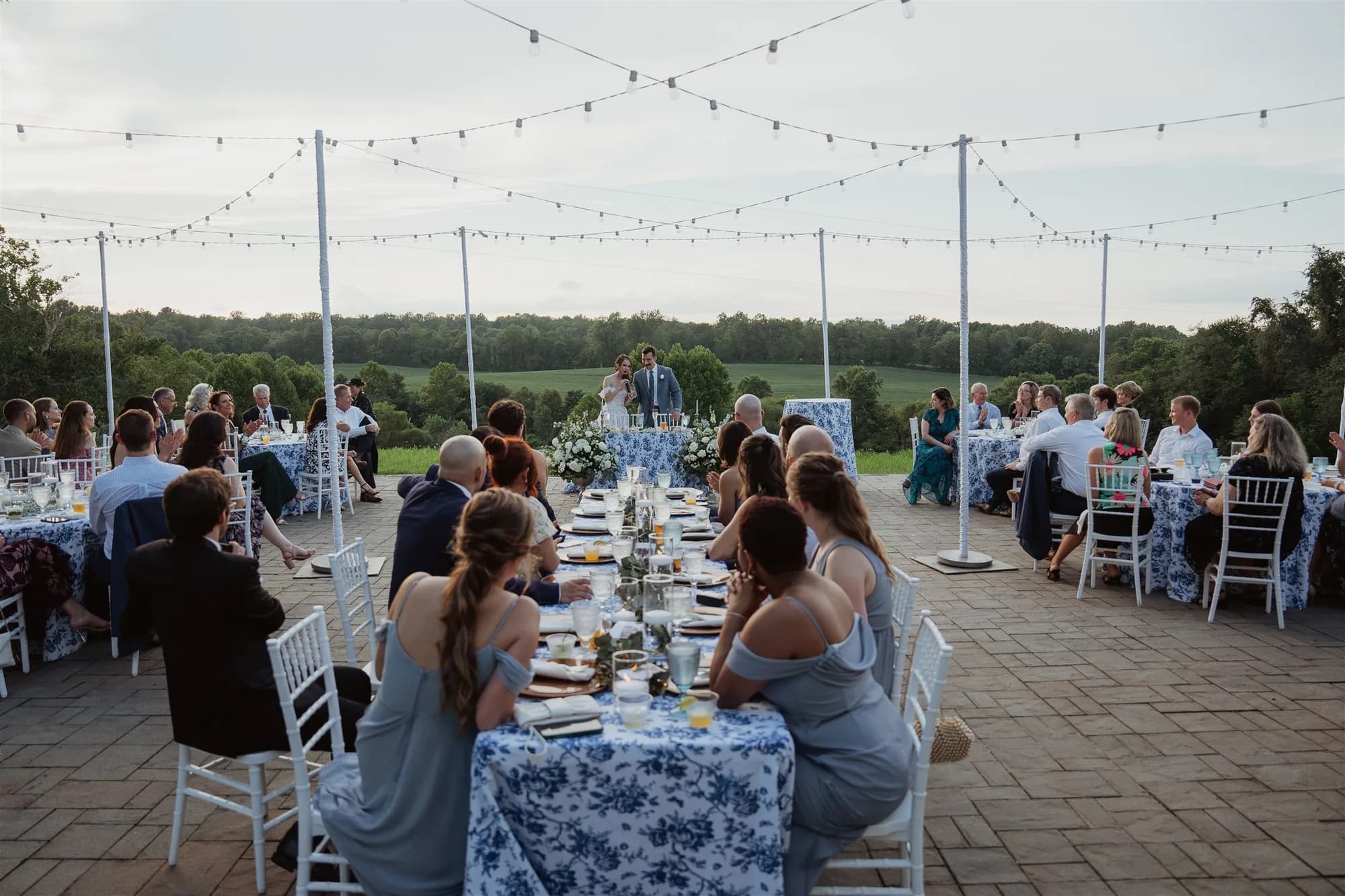 Outdoor wedding reception with long tables under string lights at rural venue