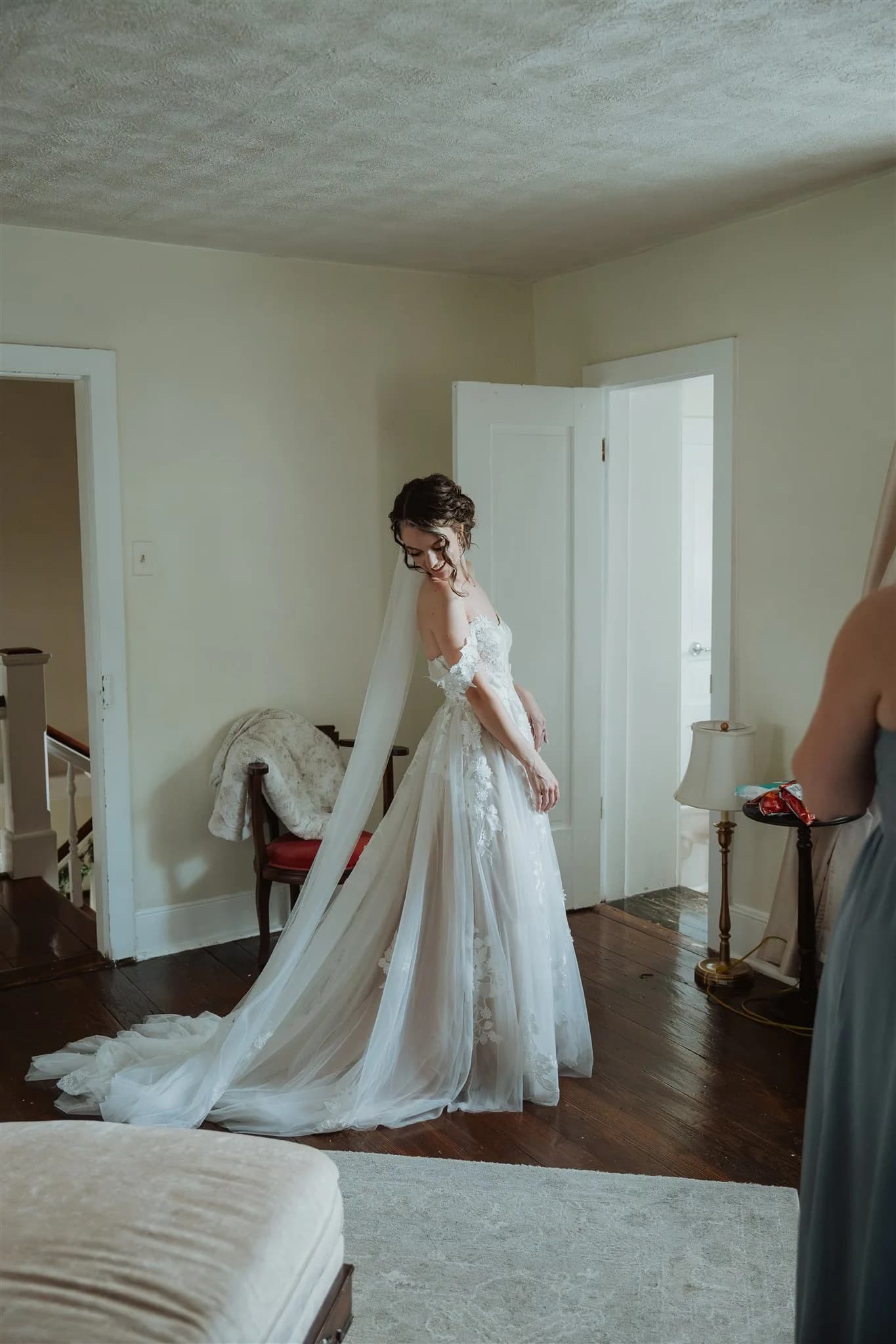 Smiling bride in lace gown and cathedral veil getting ready in a softly lit room at Rixey Manor
