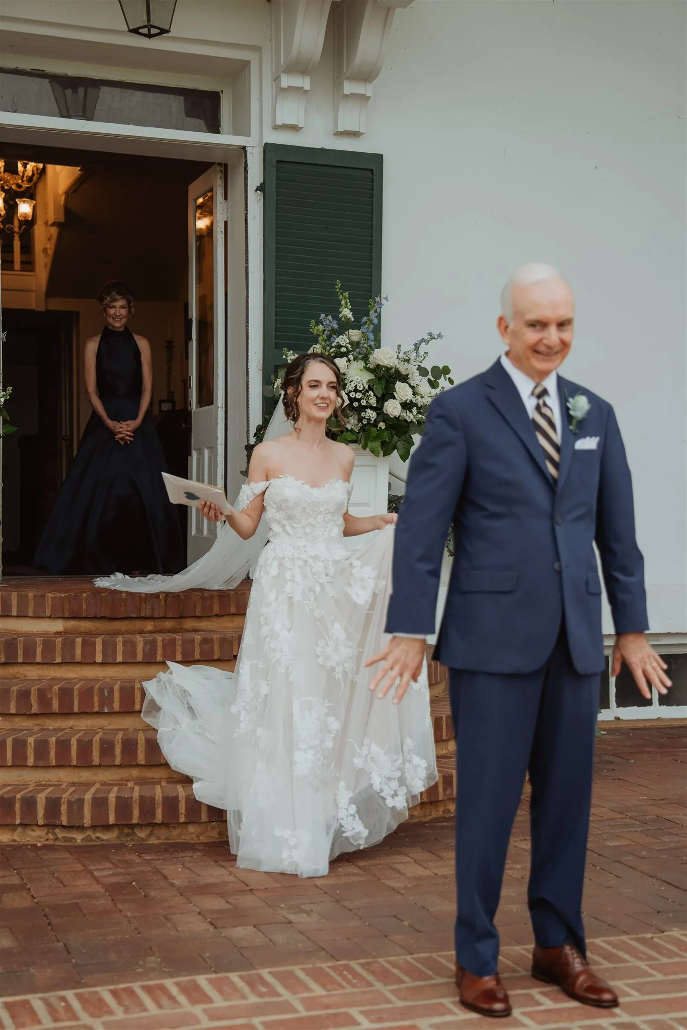 Bride descends Rixey Manor's brick steps toward a man in a blue suit in an emotional first look moment