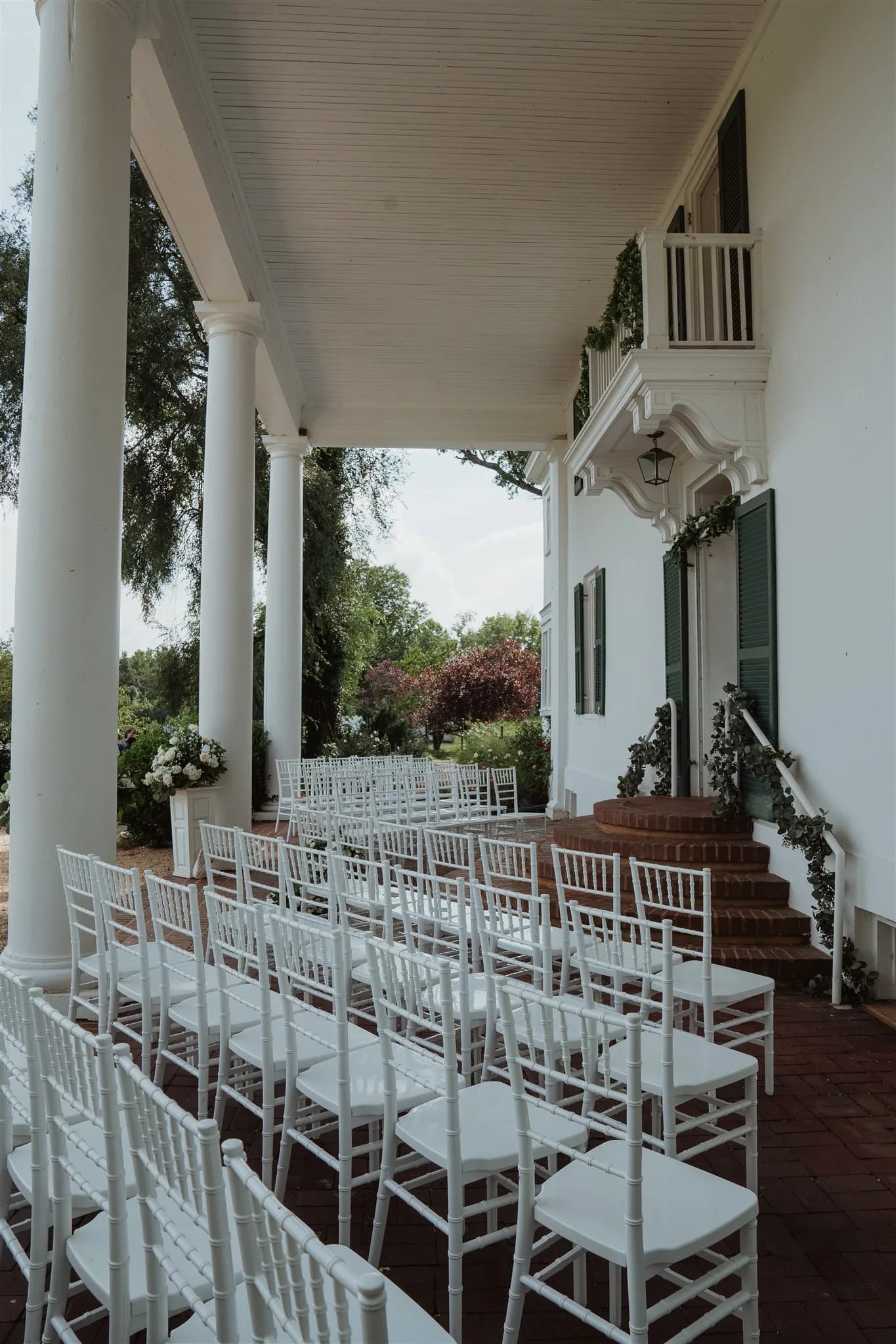 White chiavari chairs arranged for a ceremony on Rixey Manor's grand columned front porch