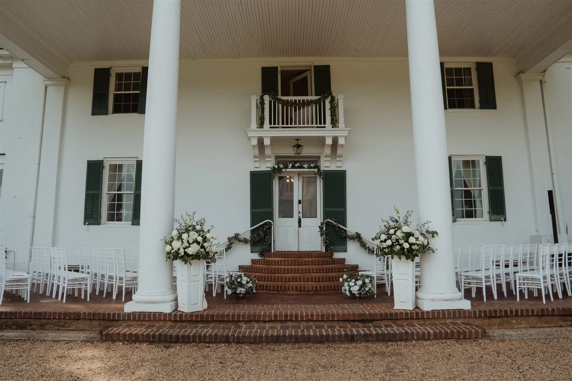 White chiavari chairs and floral urns flank the brick entrance steps of Rixey Manor before a wedding ceremony