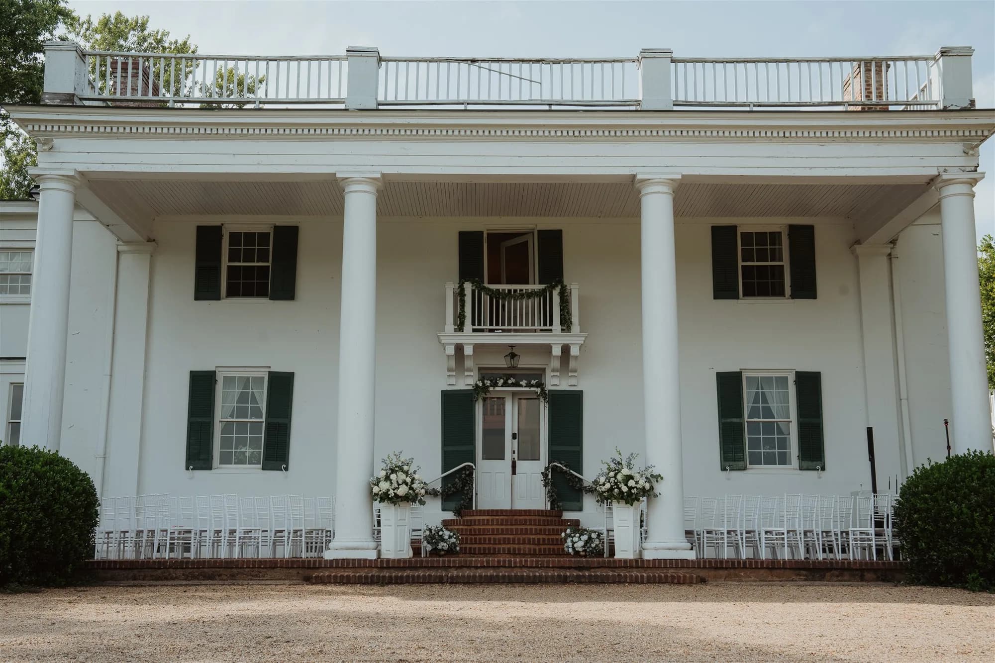 White neoclassical manor with columns, brick walkway, and landscaping at Rixey Manor venue