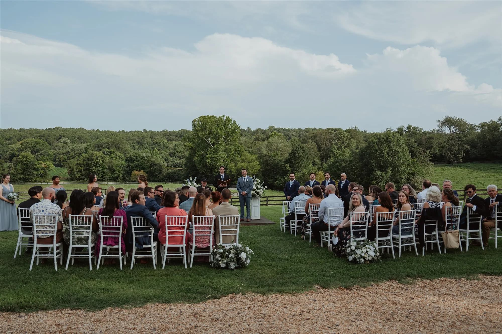 Aerial view of outdoor wedding ceremony on lush Virginia grounds with guests seated in white chairs