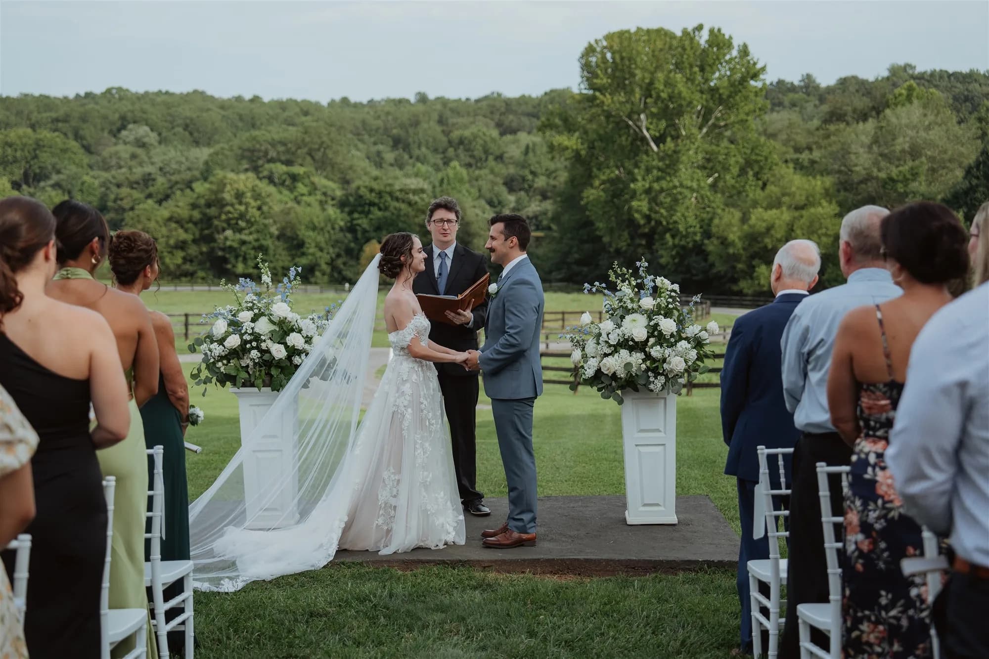 Bride and groom exchange vows at Rixey Manor outdoor ceremony with white floral pillars and lush Virginia countryside backdrop