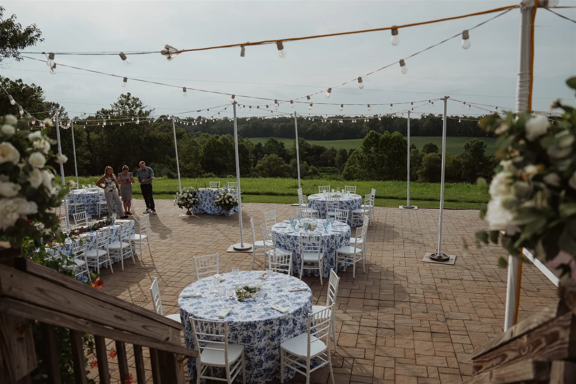 Outdoor wedding reception setup at Rixey Manor with round tables, string lights, and countryside views