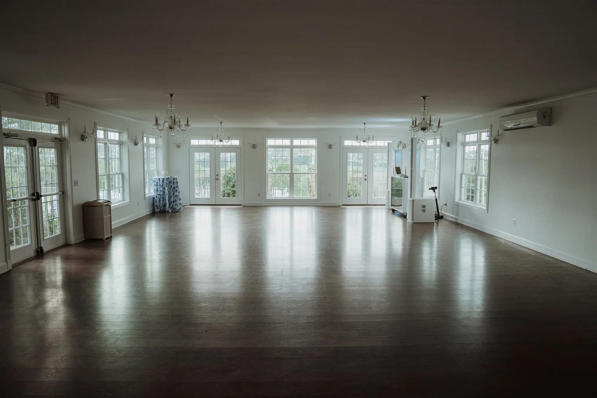 Empty hardwood ballroom with chandeliers and floor-to-ceiling windows at Rixey Manor estate