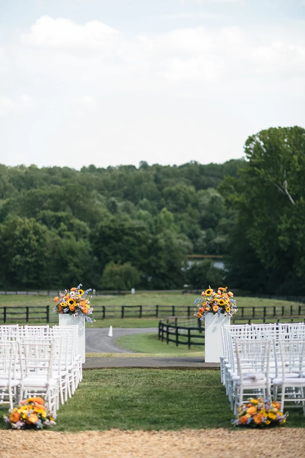 Sunflower-adorned outdoor ceremony aisle with white chairs overlooking Rixey Manor's lush Virginia countryside