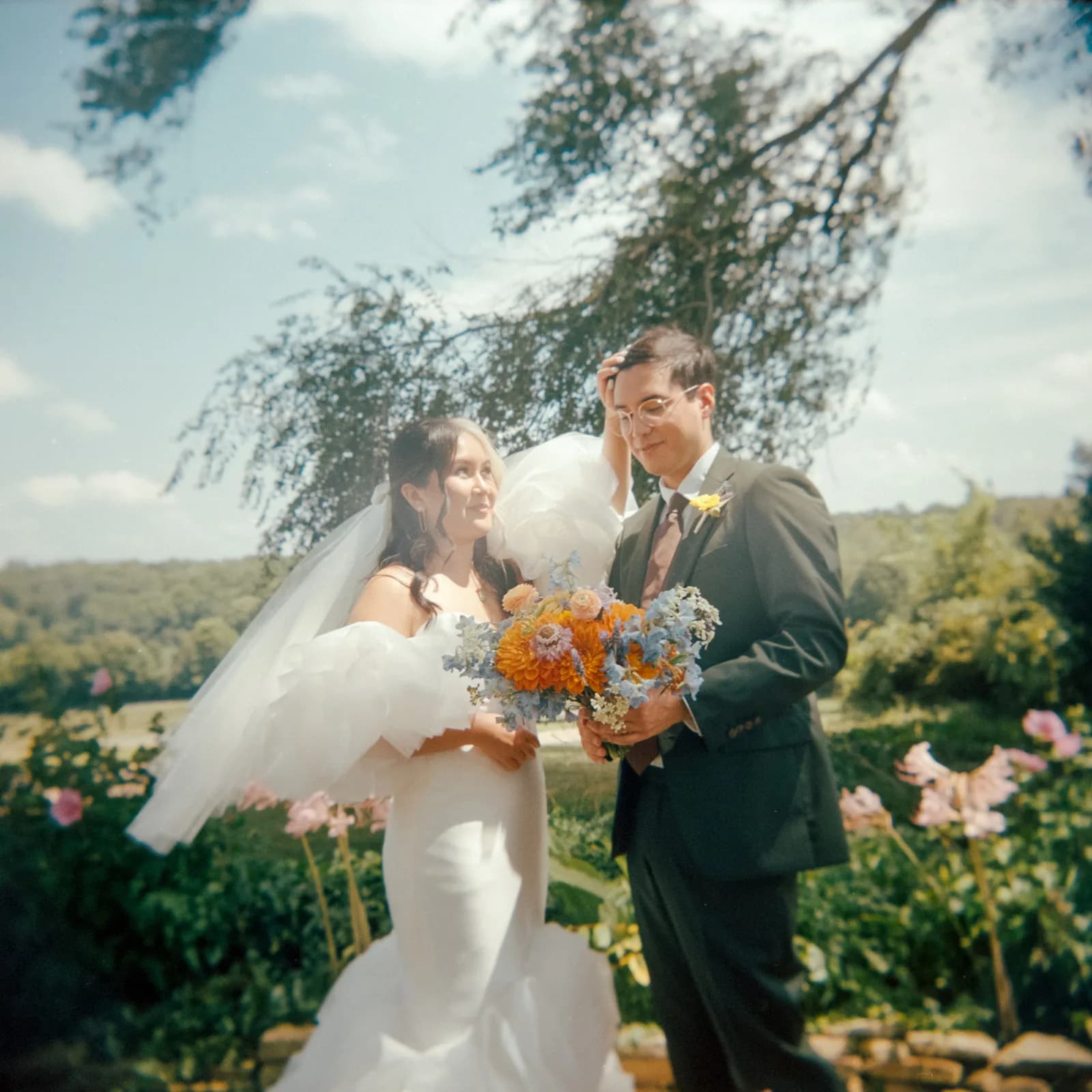 Bride and groom share a tender moment in Rixey Manor gardens, veil billowing with colorful wildflower bouquet