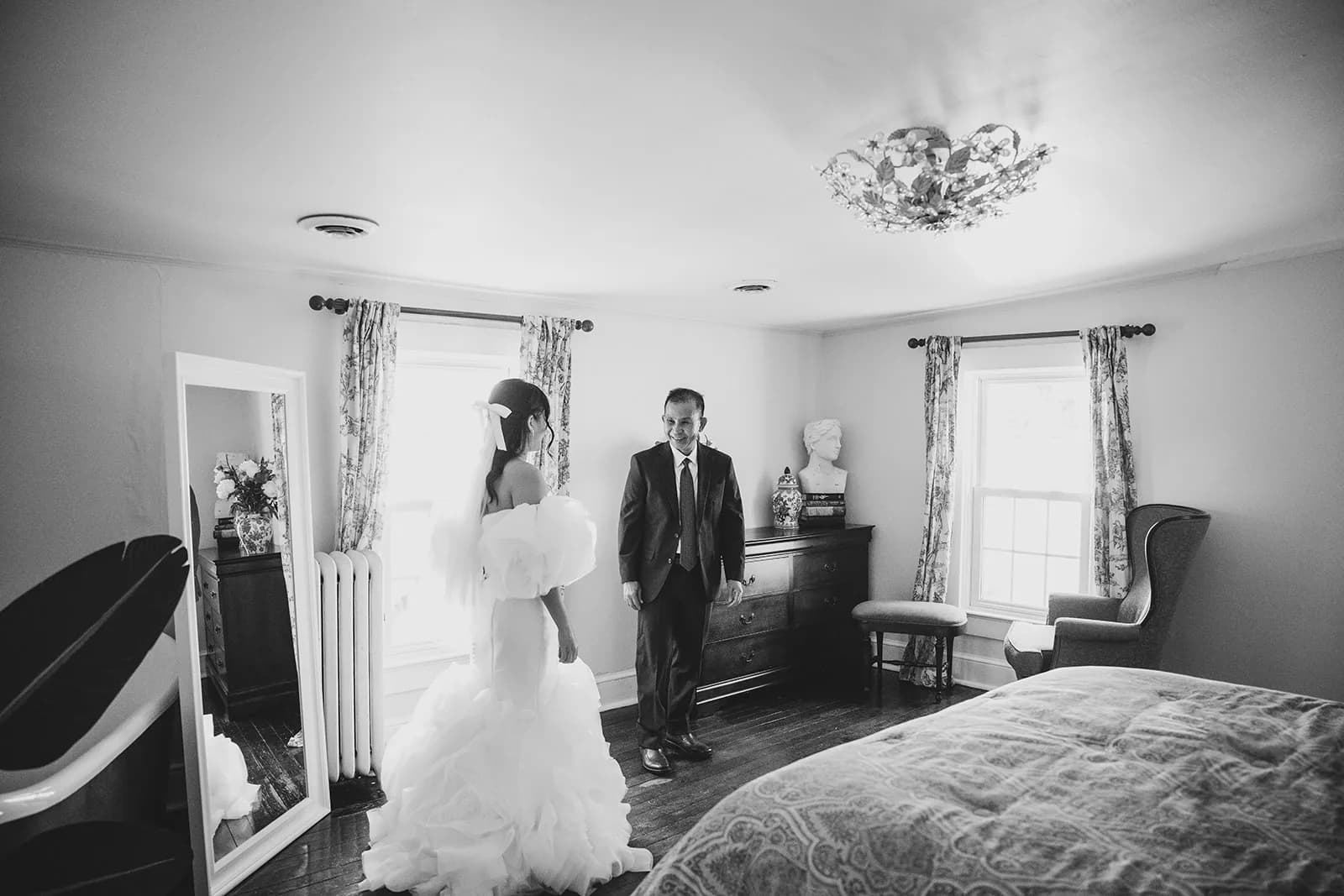 Bride and groom share a first look moment in an elegant Rixey Manor bedroom with chandelier and vintage decor
