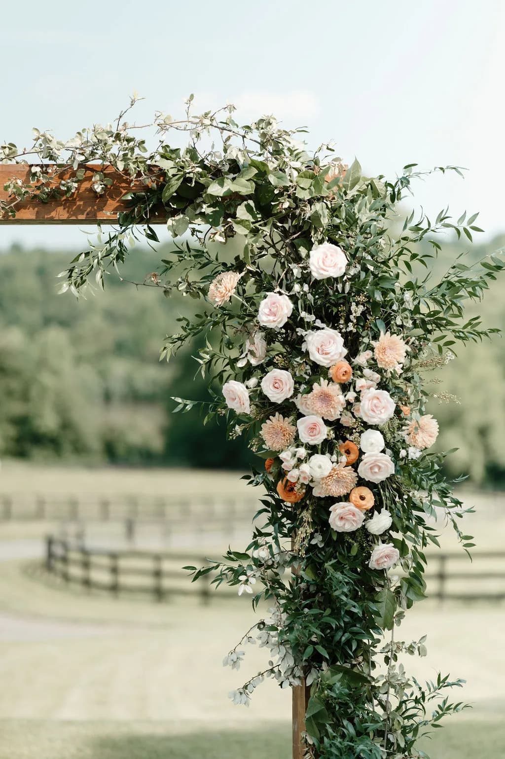 Lush floral arch with blush roses and dahlias against Rixey Manor's pastoral Virginia countryside backdrop