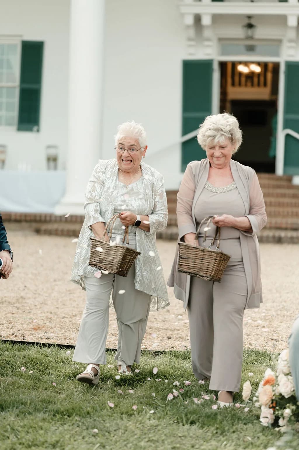 Two elderly flower girls laugh while scattering petals at Rixey Manor outdoor ceremony aisle
