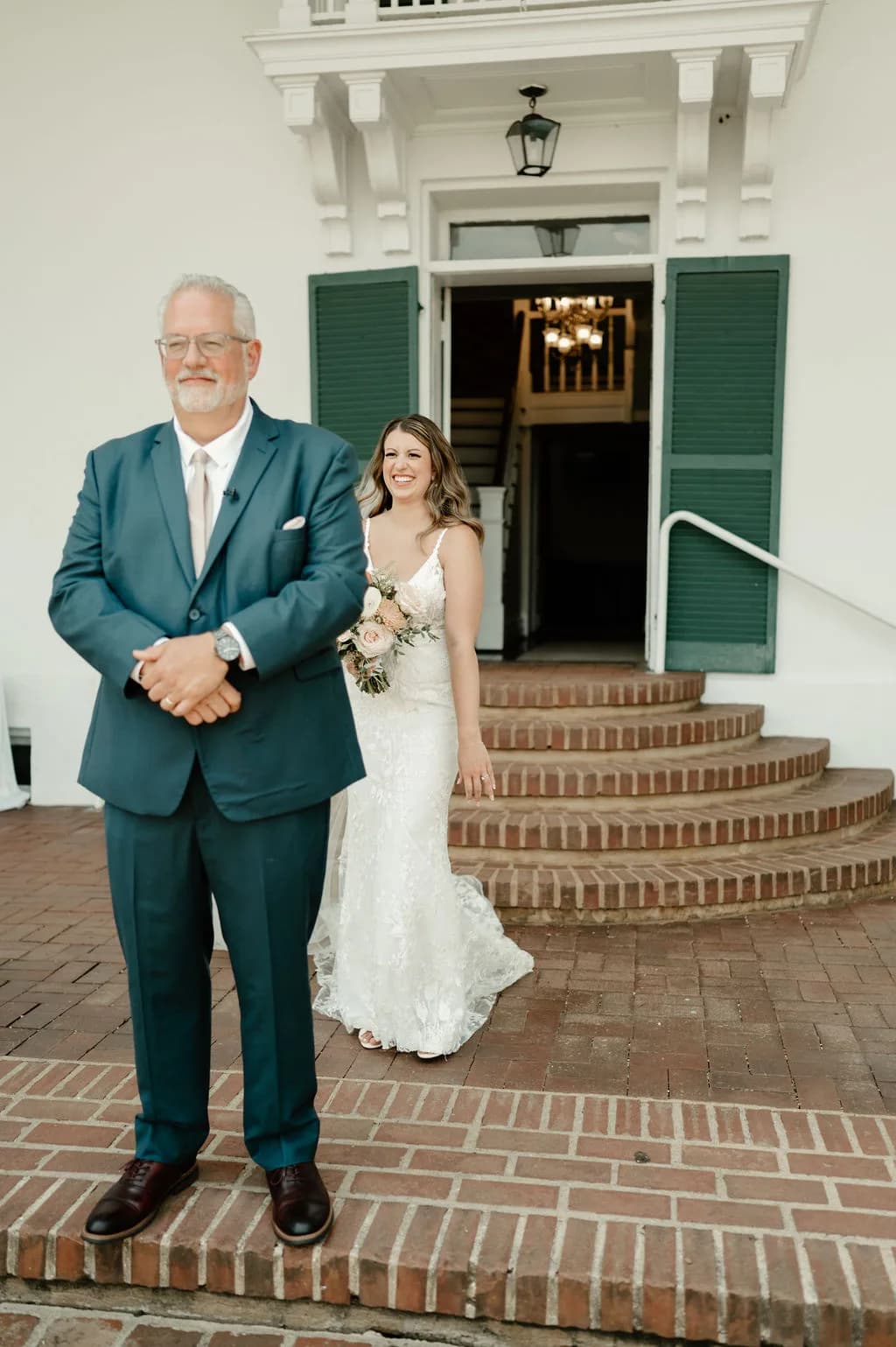 Smiling bride descends Rixey Manor's brick steps toward her father during an emotional first look