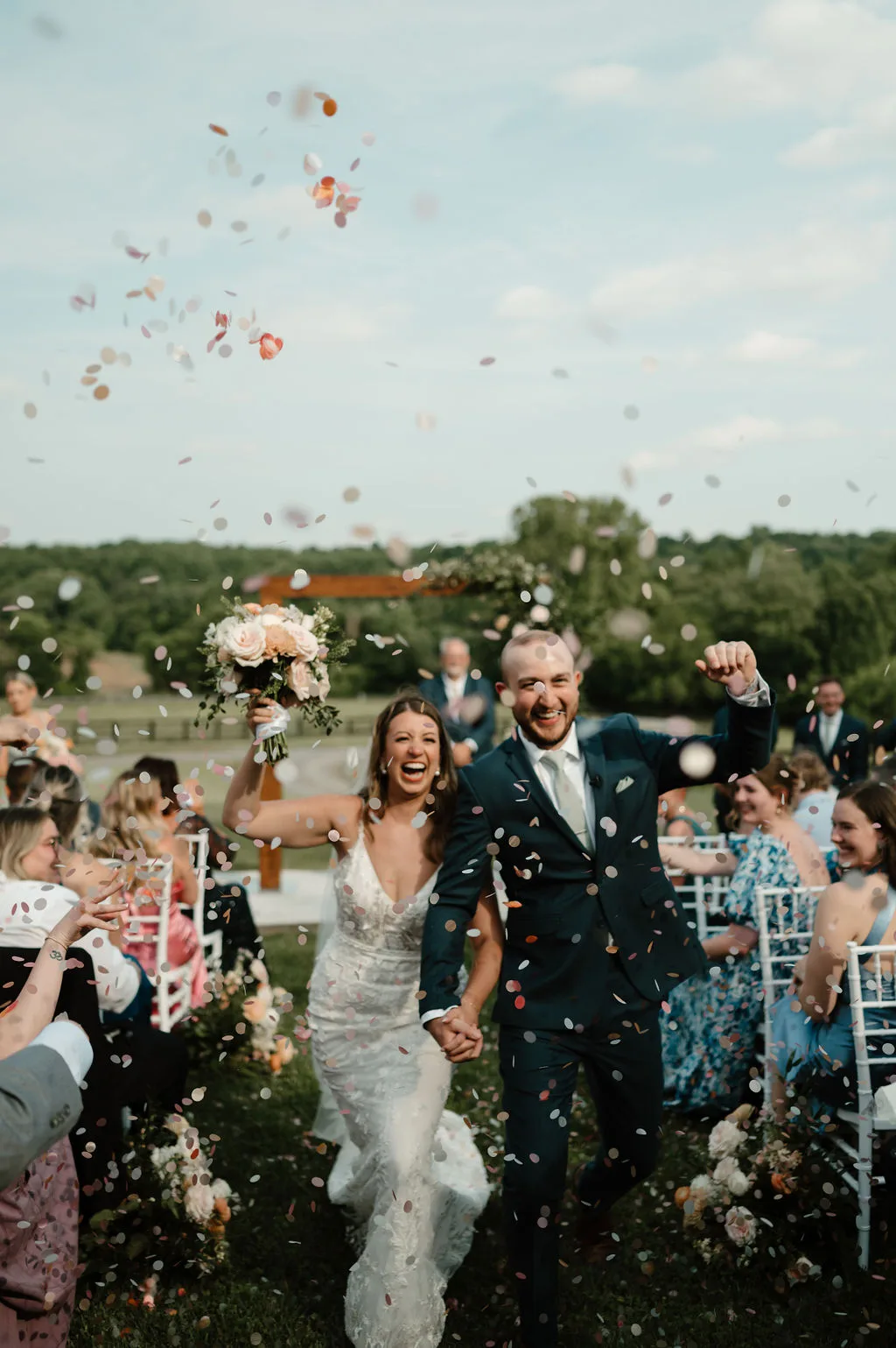 Joyful newlyweds walk back down the aisle through confetti at an outdoor Virginia estate ceremony