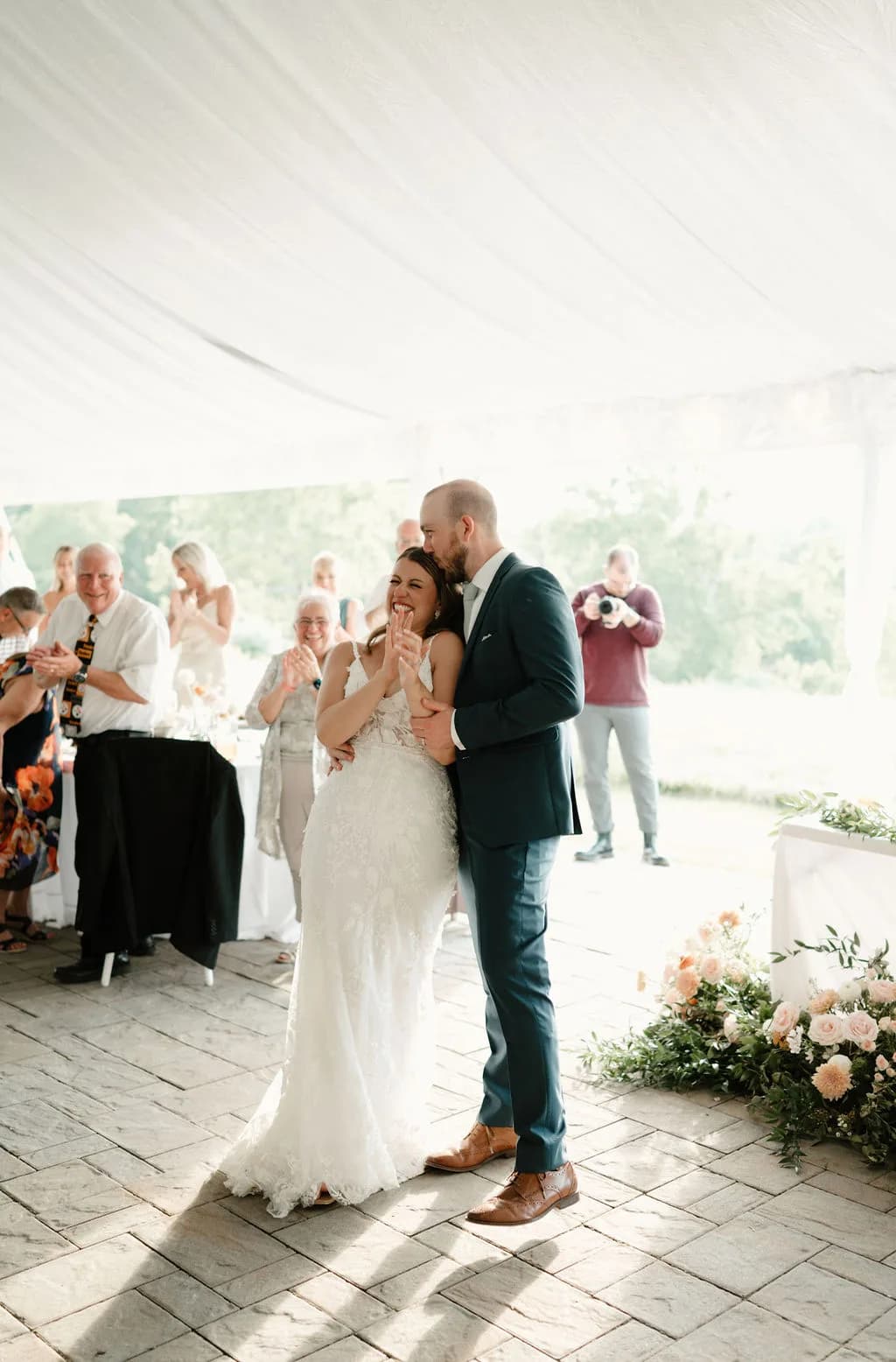Bride and groom share first dance under the tent at Rixey Manor, laughing as guests applaud around them.