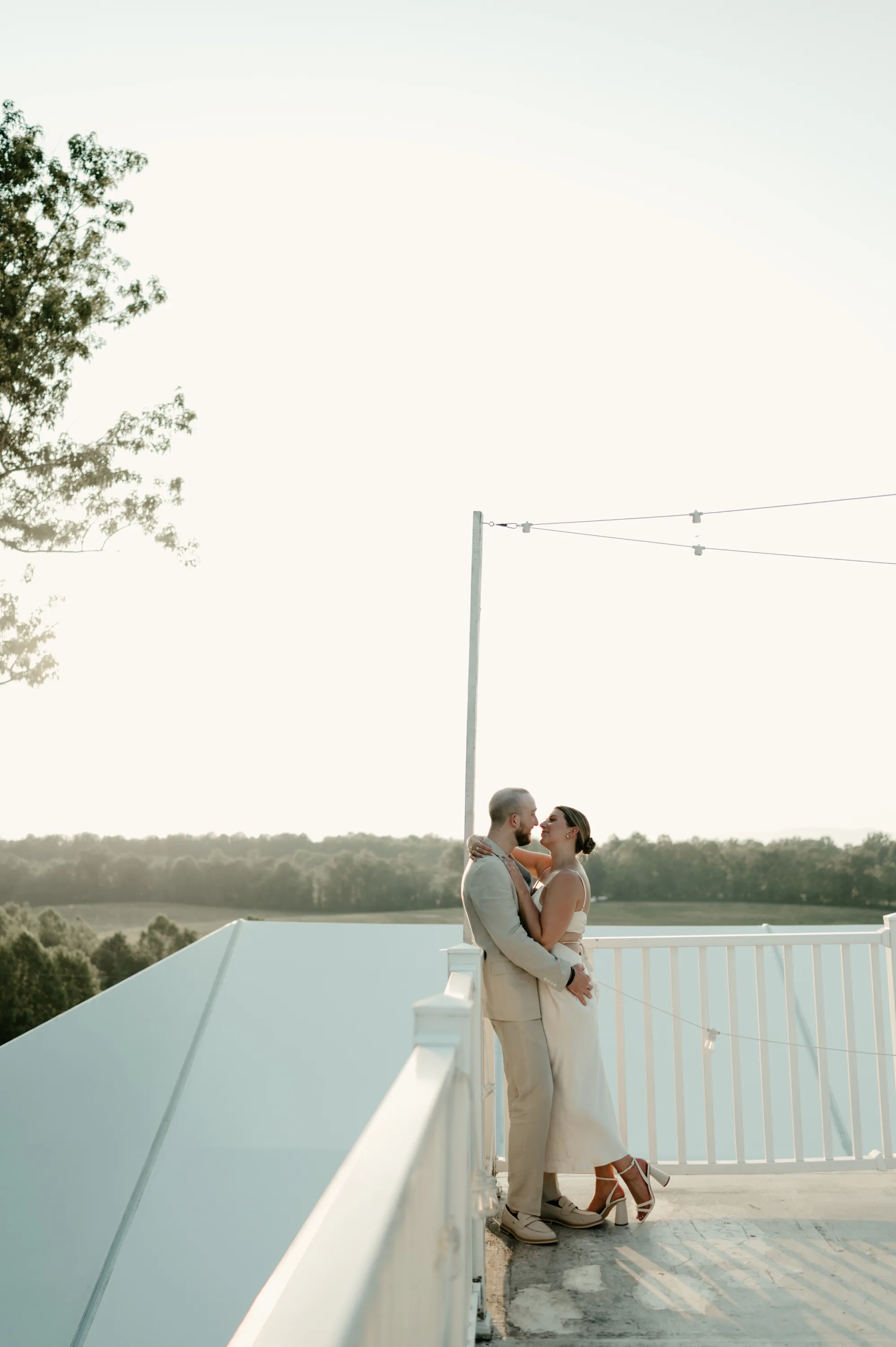 Couple sharing a kiss on the Rixey Manor rooftop terrace at golden hour with rolling Virginia countryside behind them.