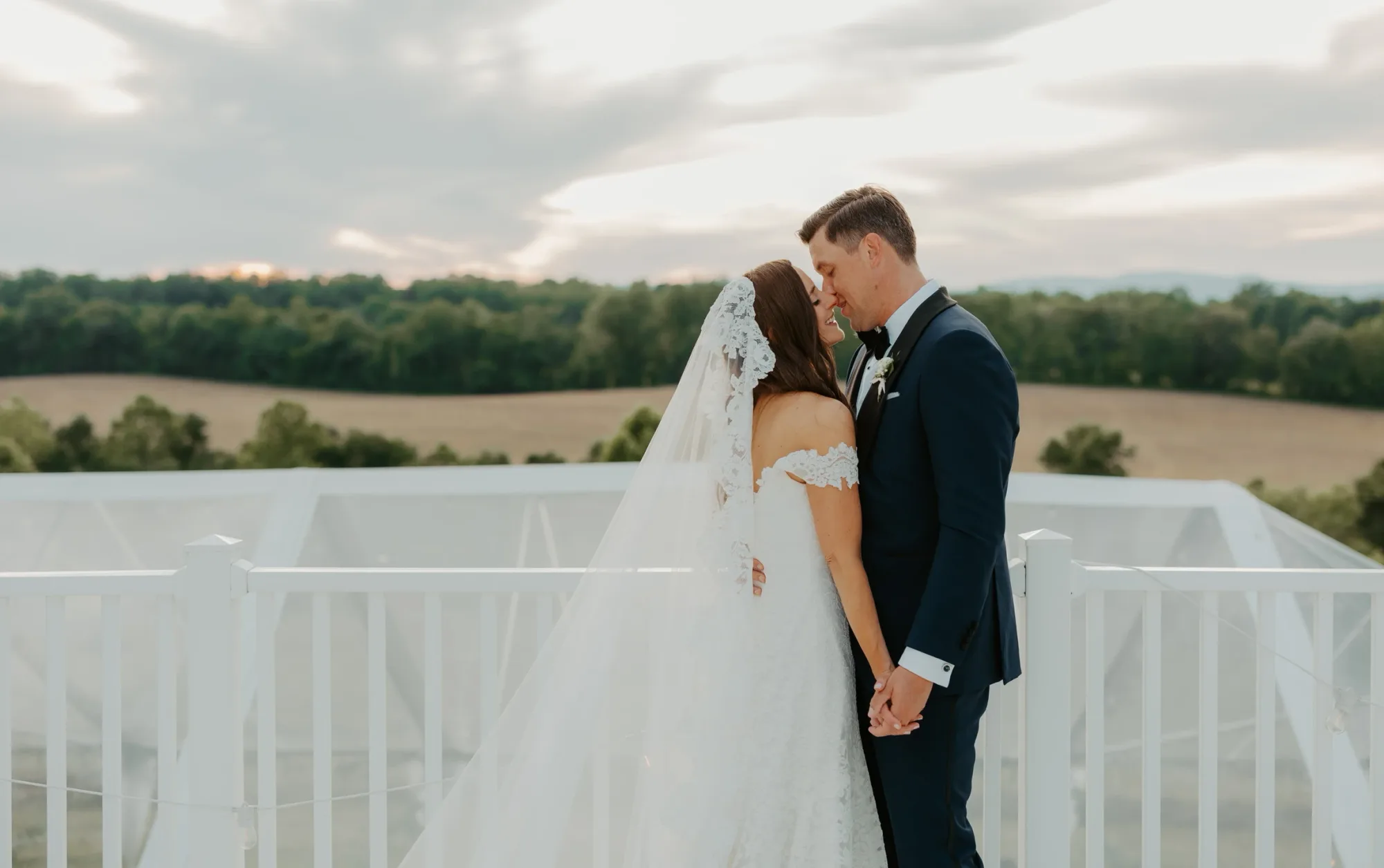 Bride and groom share a tender moment on Rixey Manor's rooftop terrace with rolling Virginia countryside at sunset