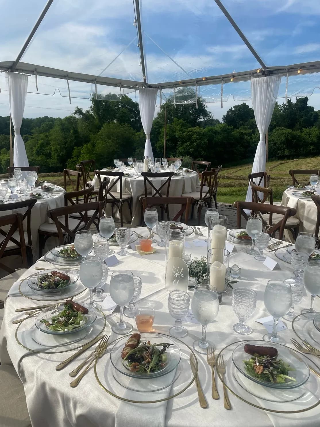Elegant reception tables set under a clear tent at Rixey Manor with rolling Virginia countryside views