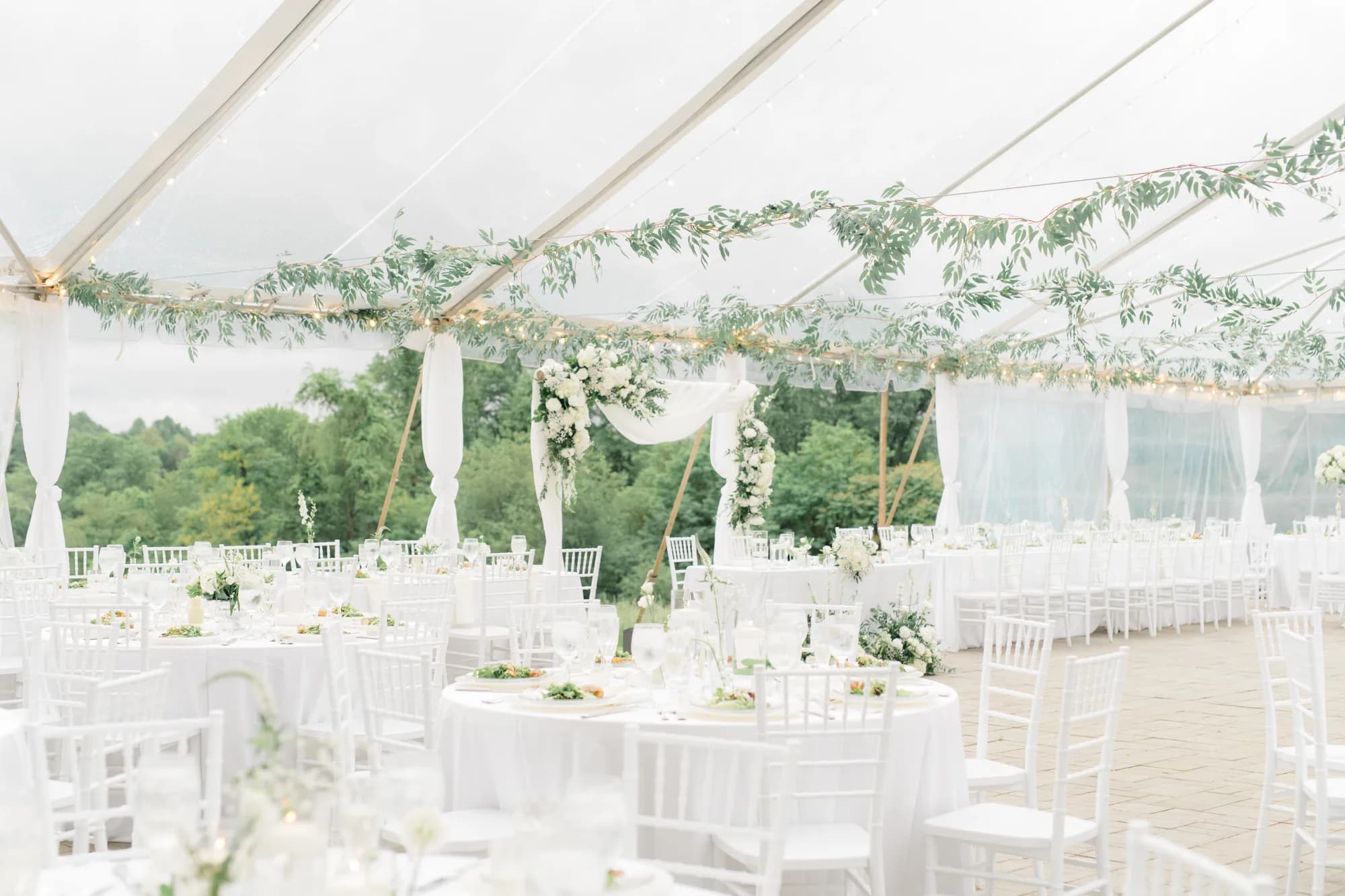 Elegant white reception tent at Rixey Manor draped with greenery garlands, white Chiavari chairs, and floral centerpieces