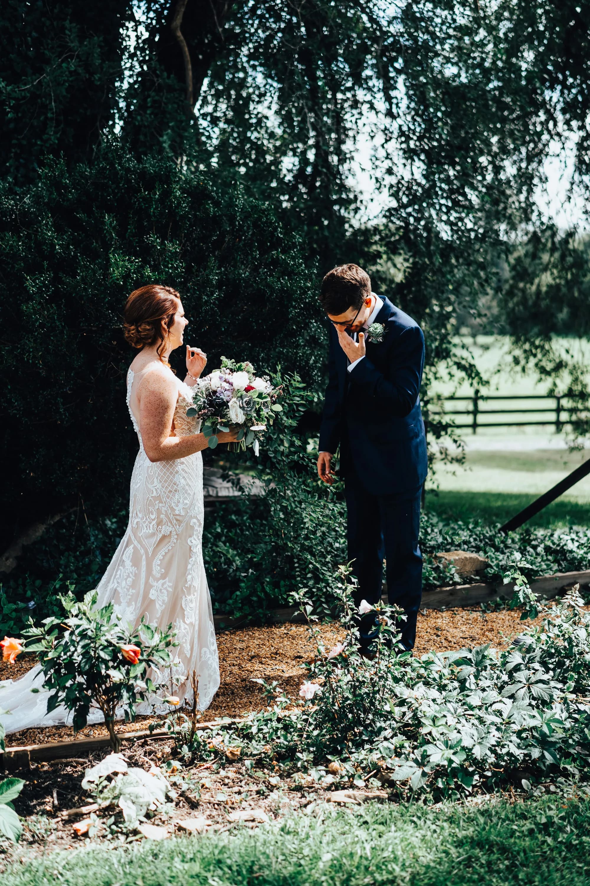 Groom overcome with emotion during first look as bride holds bouquet in a lush garden setting