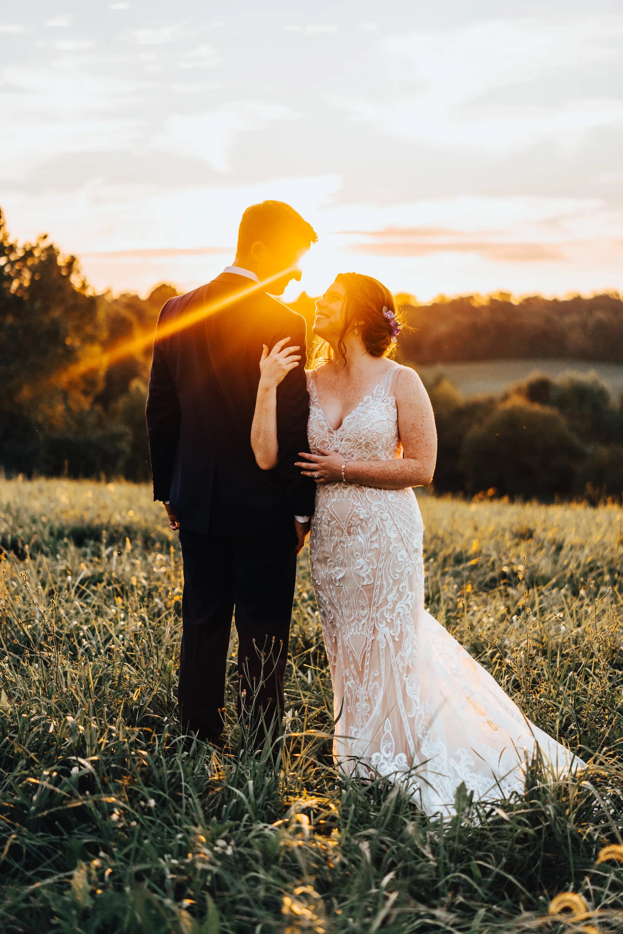 Bride and groom share a golden hour moment in a sunlit Virginia field, glowing sunset behind them