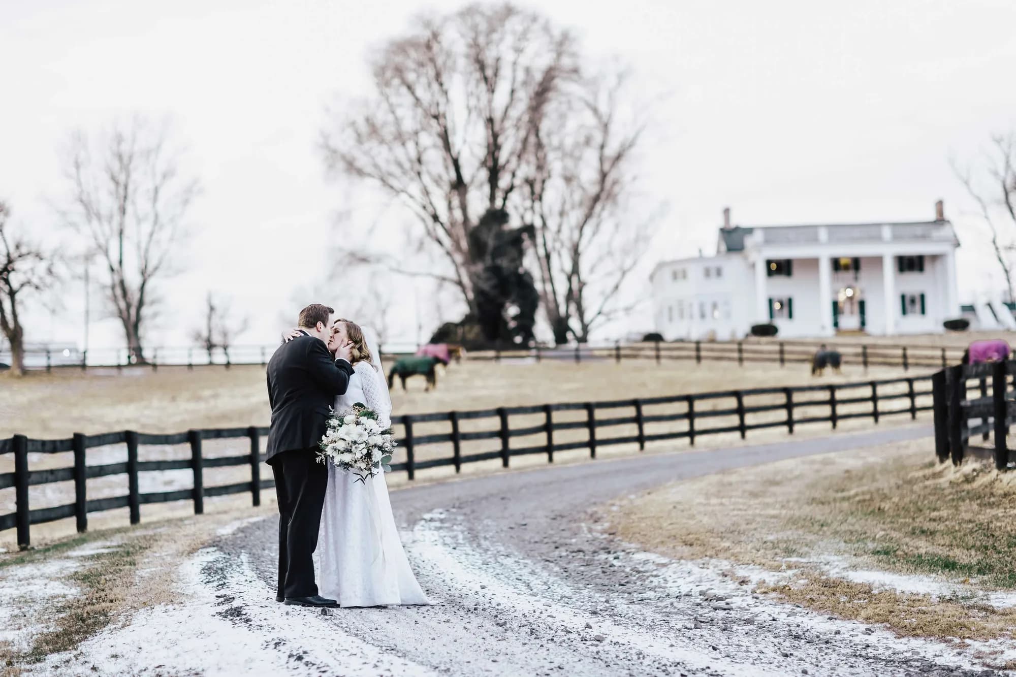 Bride and groom share a kiss on snowy lane outside Rixey Manor estate in winter