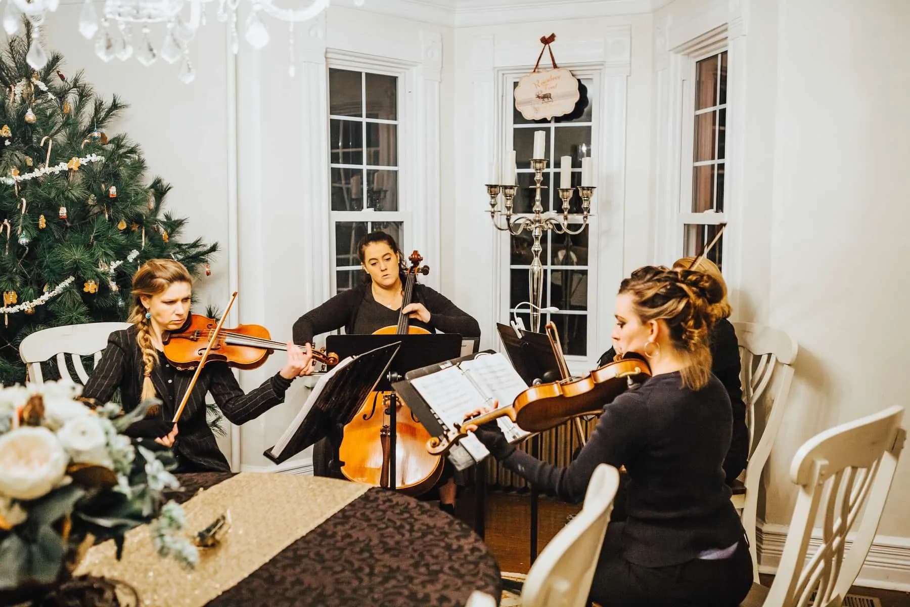 String quartet performing in an elegant white-paneled room at Rixey Manor decorated for a winter wedding