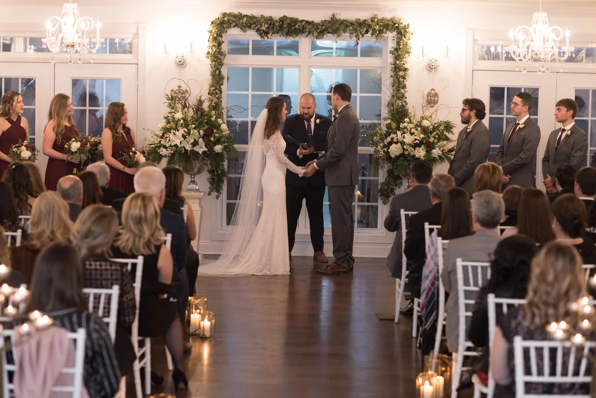 Bride and groom exchange vows under floral arch with candlelit aisle and guests seated at Rixey Manor ceremony