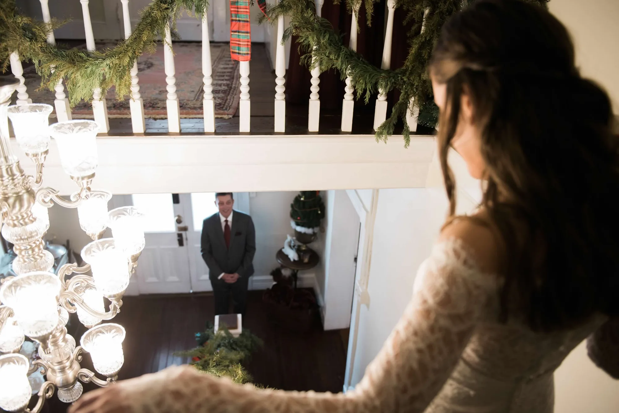 Bride descends staircase toward waiting groom in Rixey Manor's grand foyer during first look moment