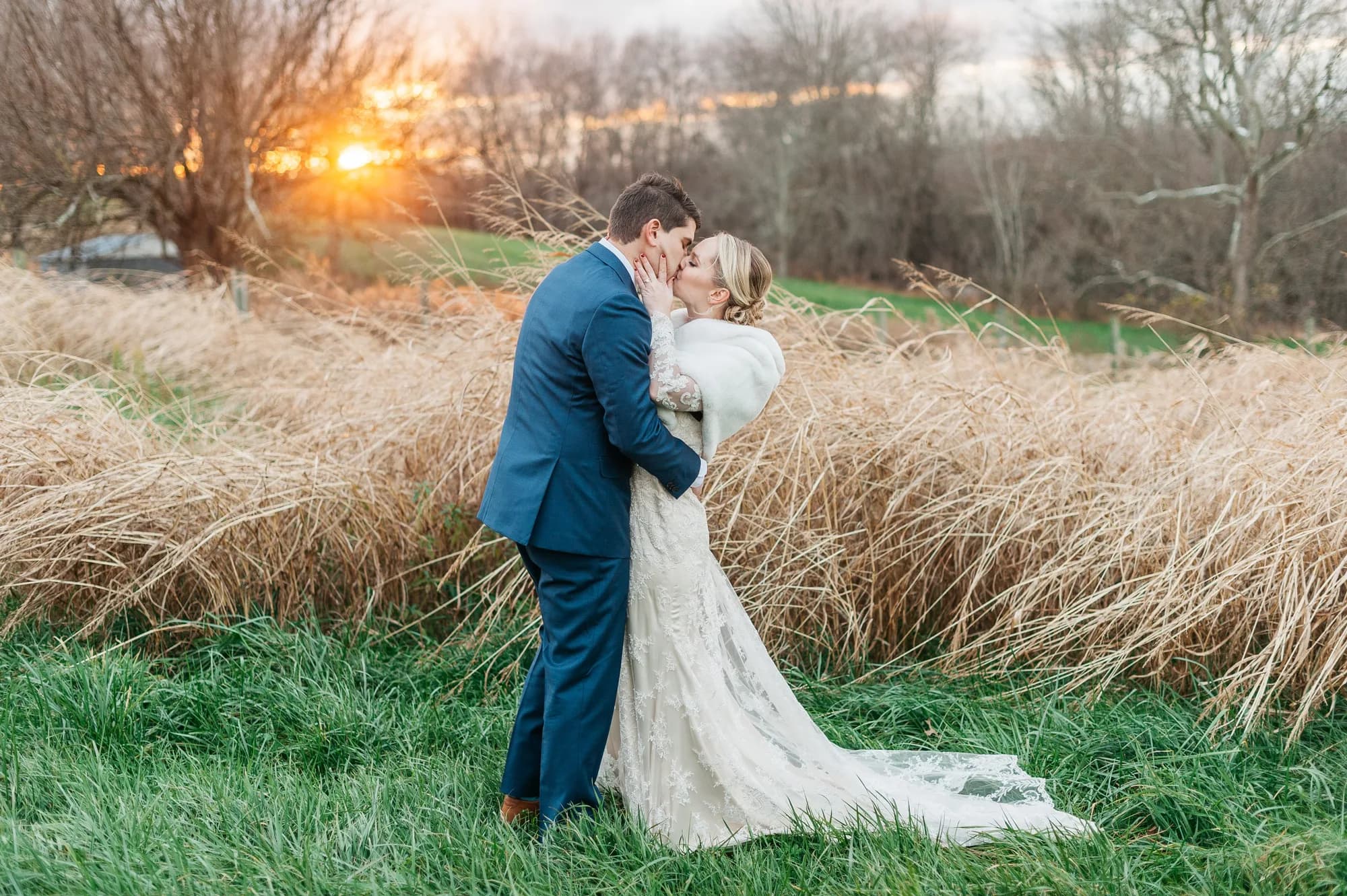 Bride and groom share a golden hour kiss in a field of wild grasses at sunset in rural Virginia