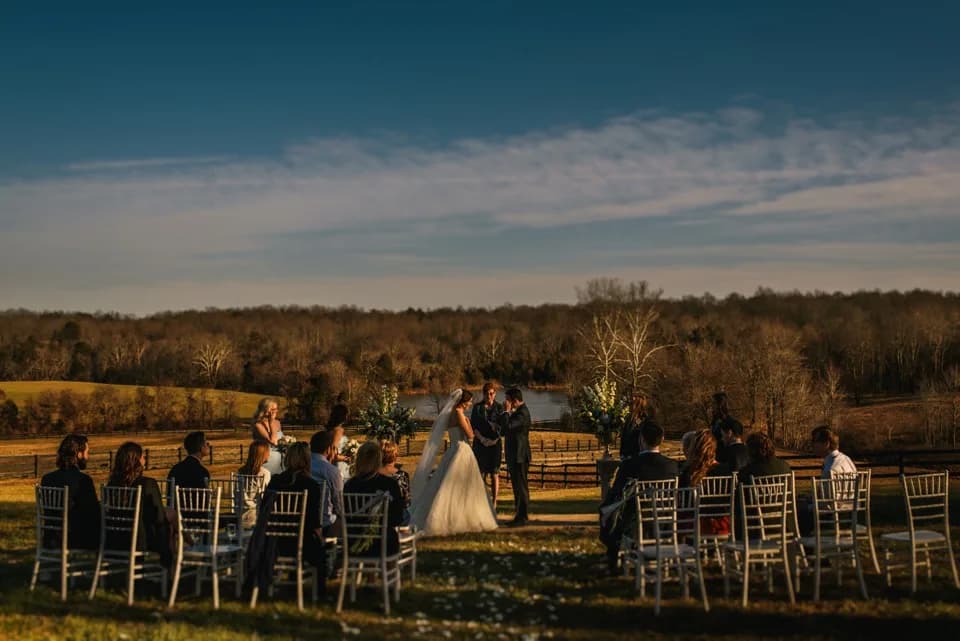 Couple exchanges vows at golden-hour outdoor ceremony overlooking Rixey Manor's rolling fields and lake