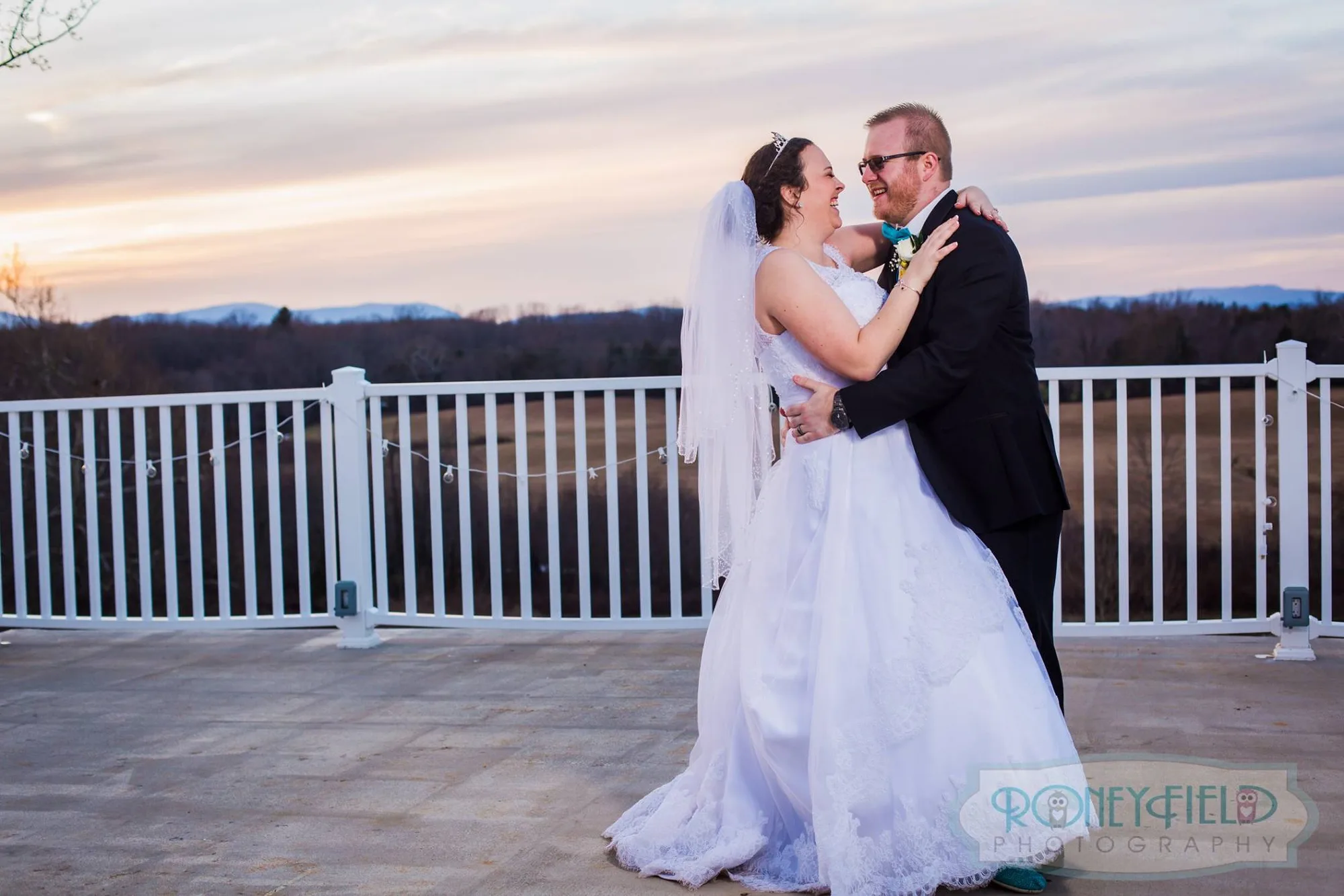 Bride and groom laughing together on Rixey Manor terrace at sunset with mountain views behind them