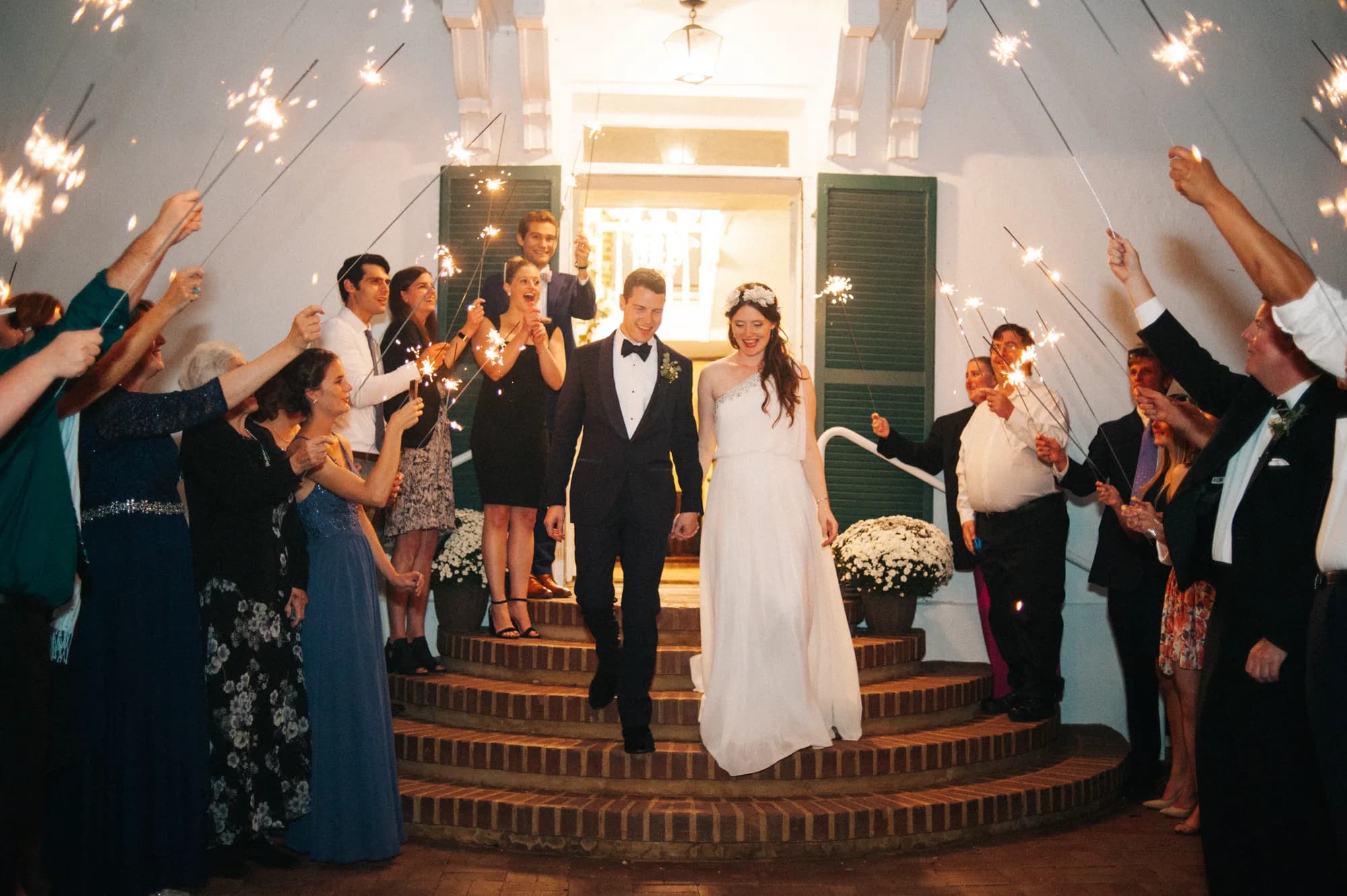 Bride and groom exit Rixey Manor through a sparkler tunnel surrounded by cheering guests on the carriage steps