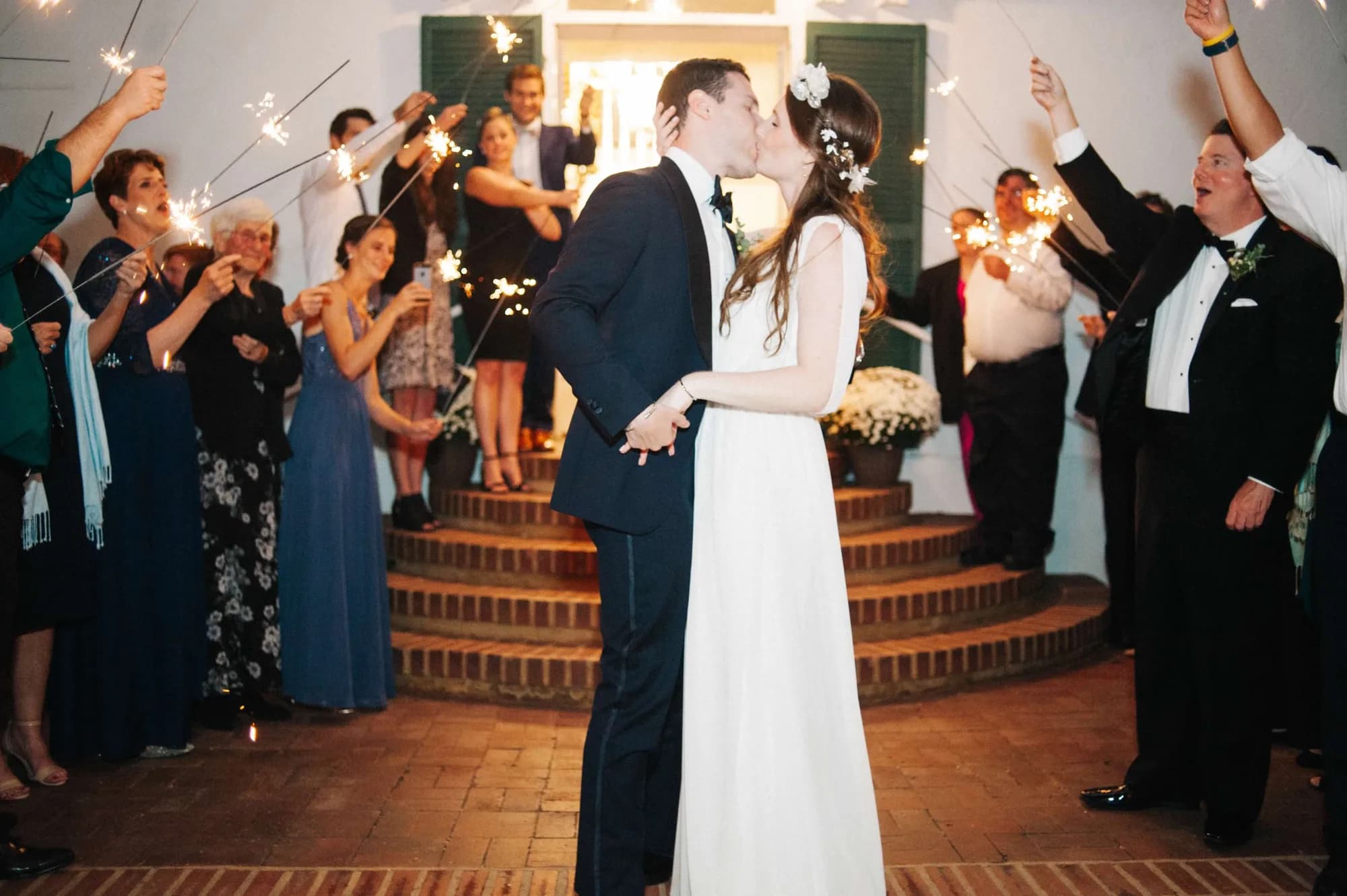 Bride and groom share a kiss during sparkler send-off on the brick terrace steps at Rixey Manor