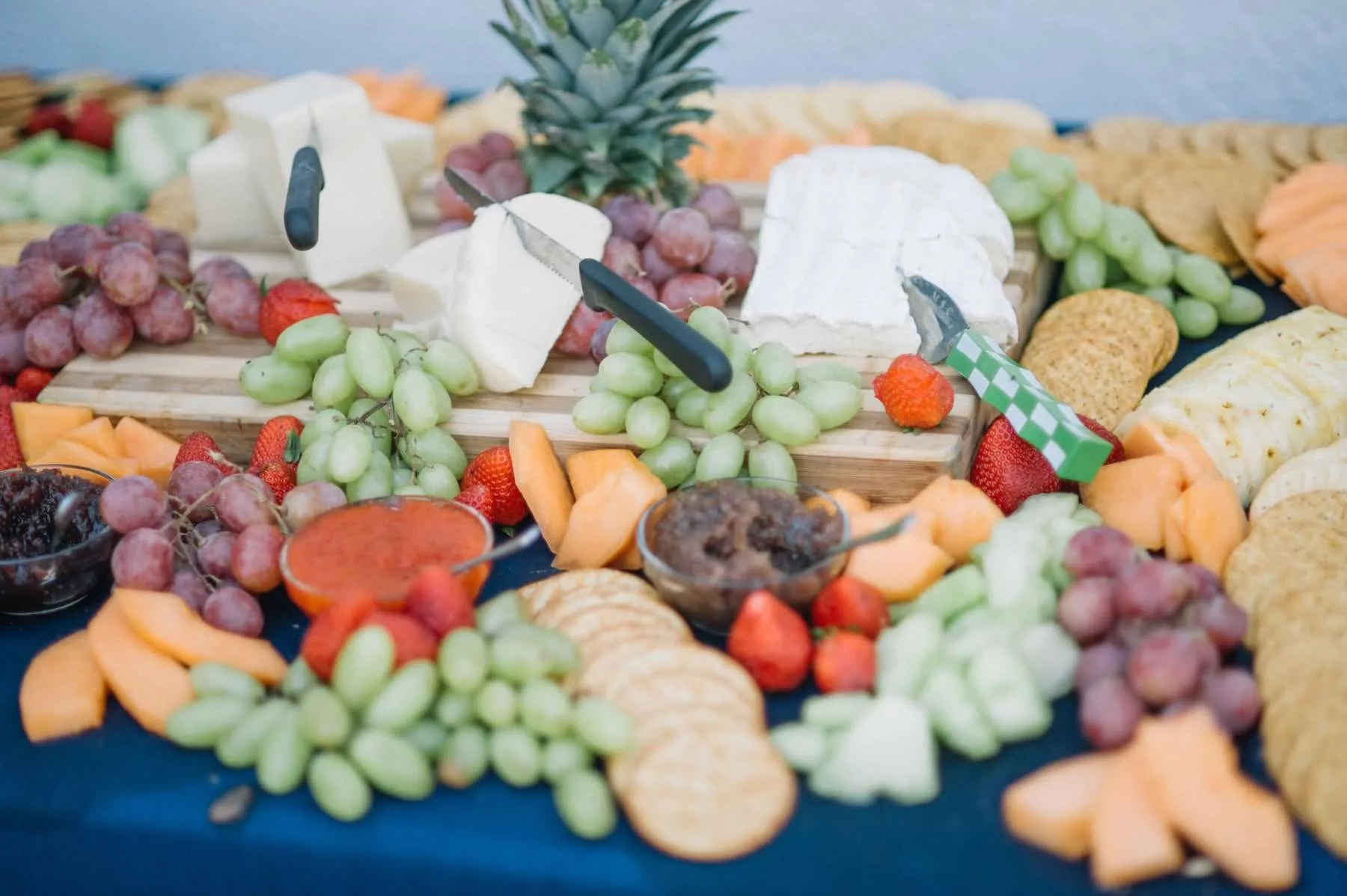 Colorful charcuterie and fruit display with grapes, crackers, cheese, and pineapple at wedding reception