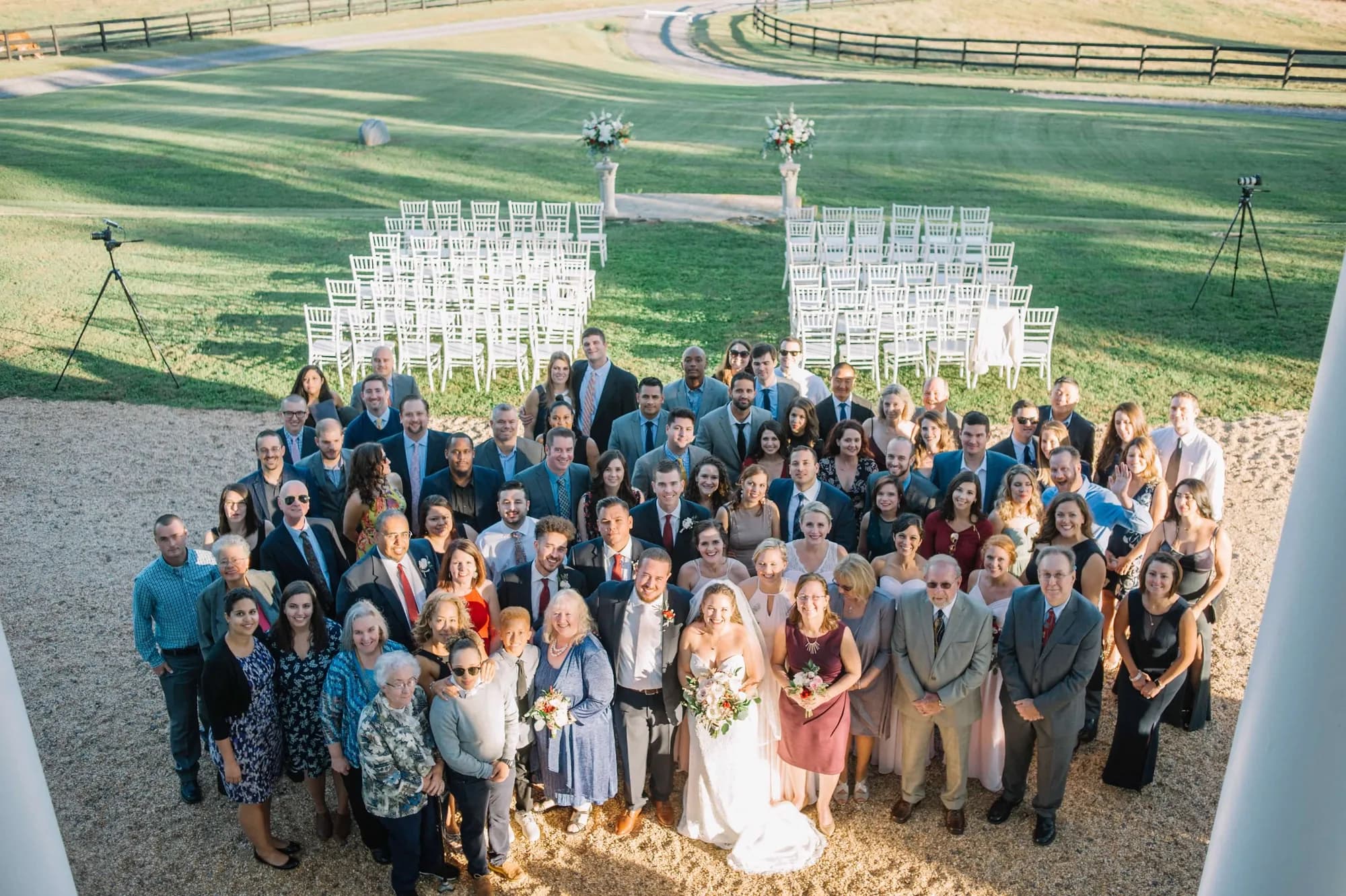 Aerial group photo of wedding guests and couple at Rixey Manor outdoor ceremony site with white chairs