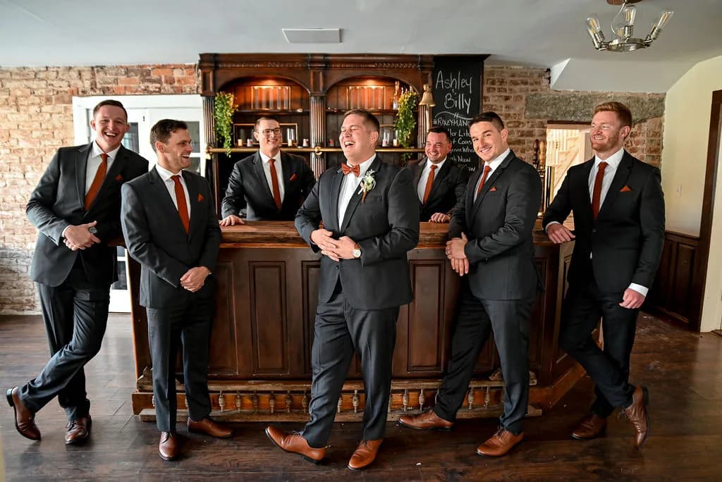 Groom and groomsmen laughing together at a rustic bar inside Rixey Manor