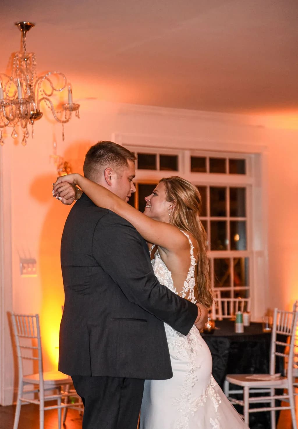 Bride laughing joyfully during first dance under crystal chandelier at Rixey Manor reception